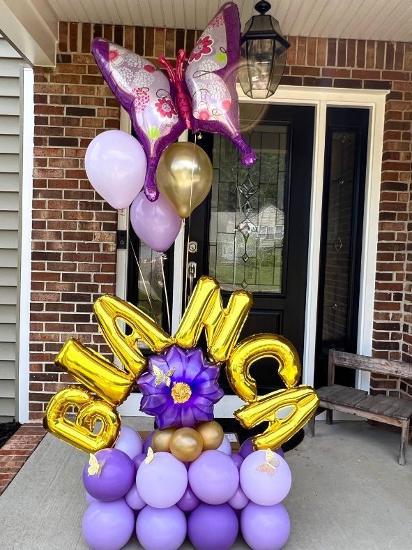 A bunch of purple and gold balloons on a porch