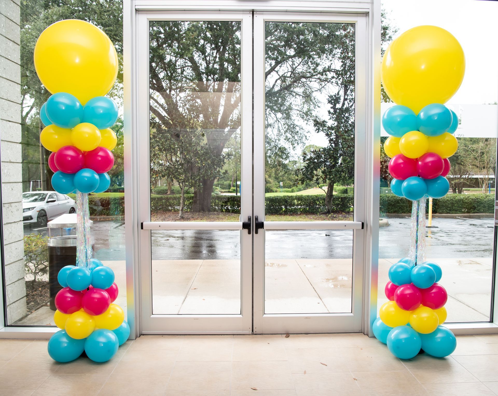 Two columns of balloons are in front of a glass door.