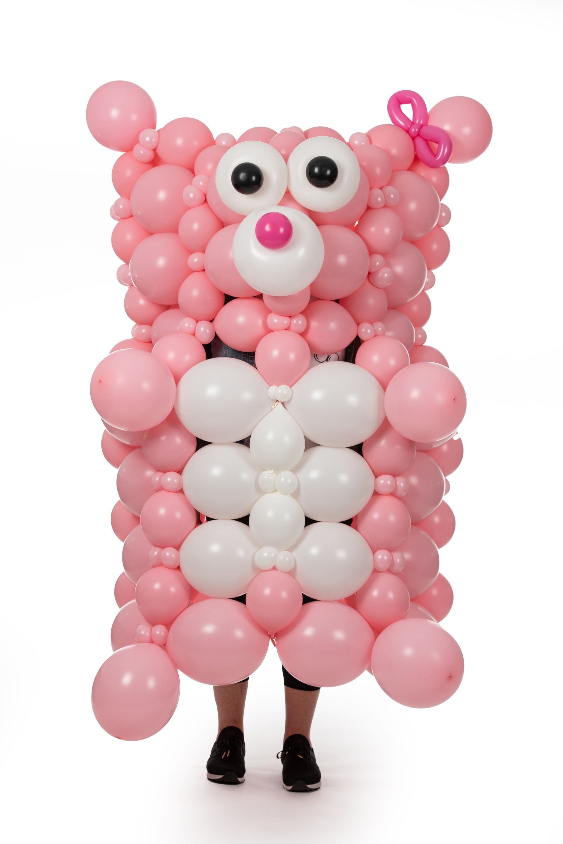 A person is wearing a costume made of pink and white balloons.