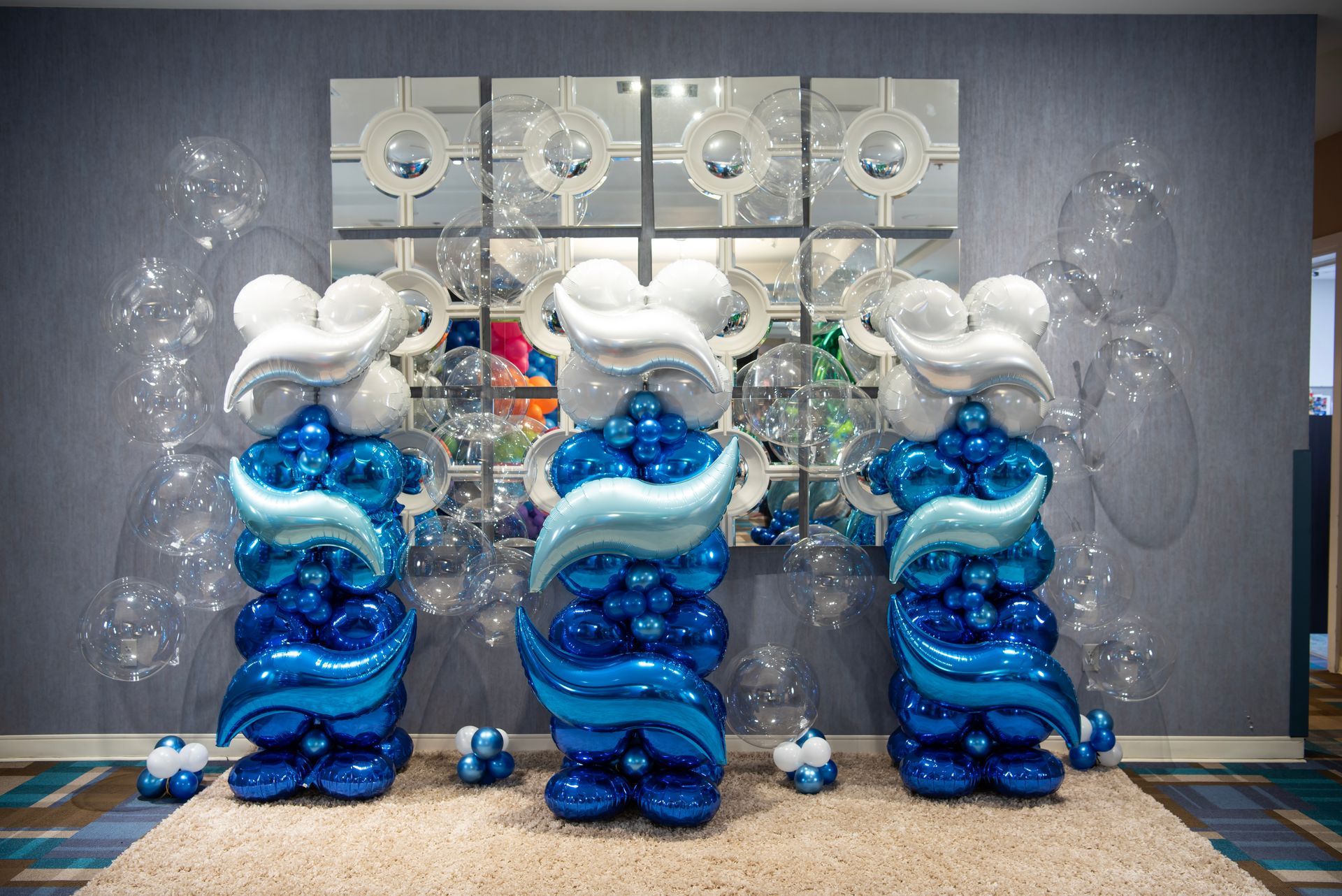 Three columns made of blue and white balloons in a room.