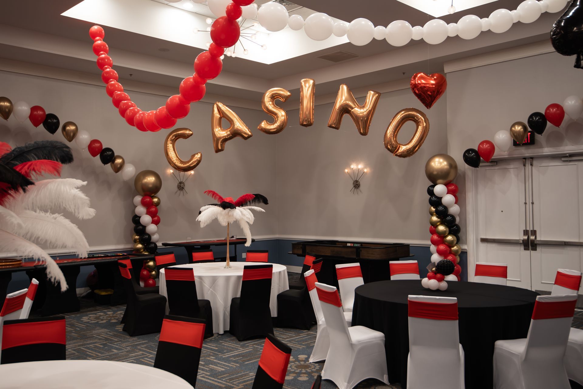 A room decorated for a casino party with tables and chairs and balloons.
