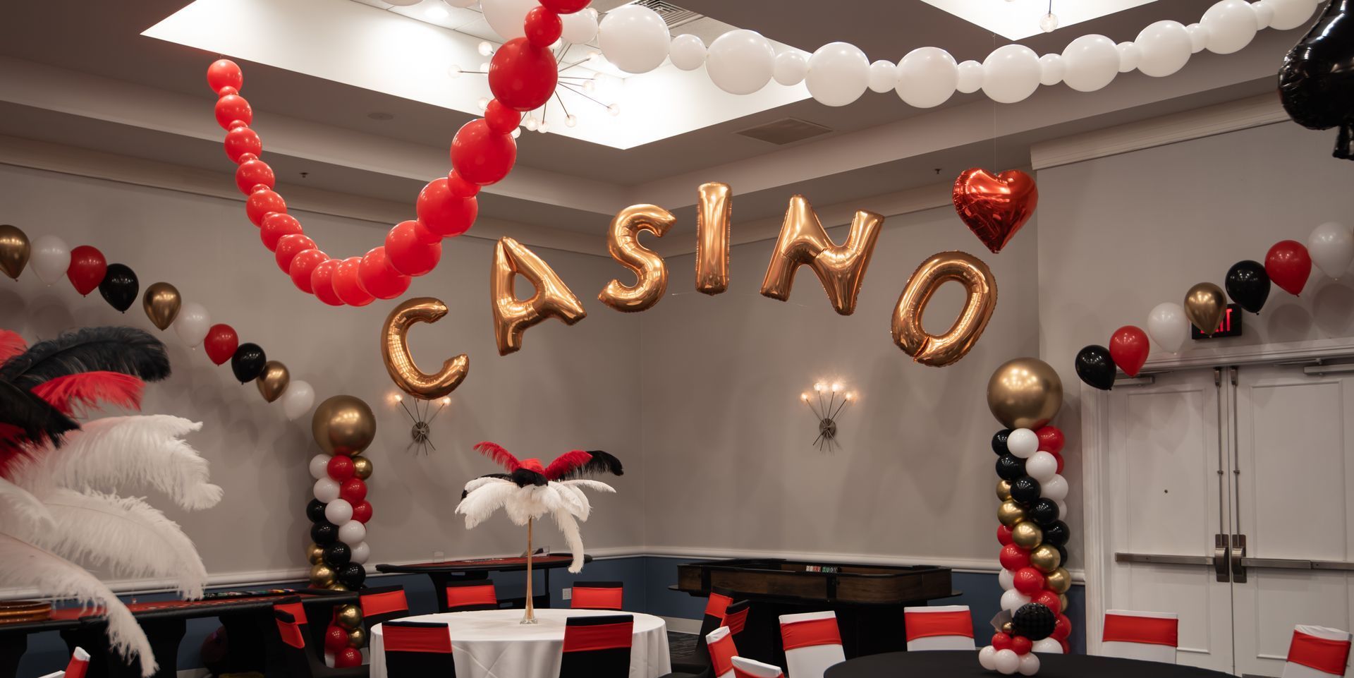 A room decorated for a casino party with balloons and feathers.