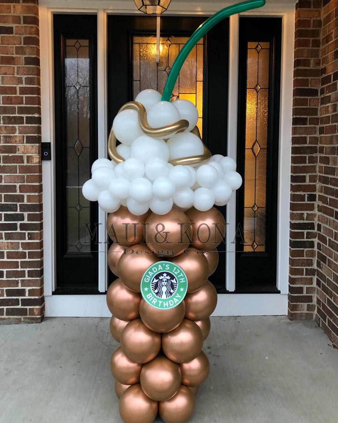 A starbucks drink made out of balloons in front of a brick building