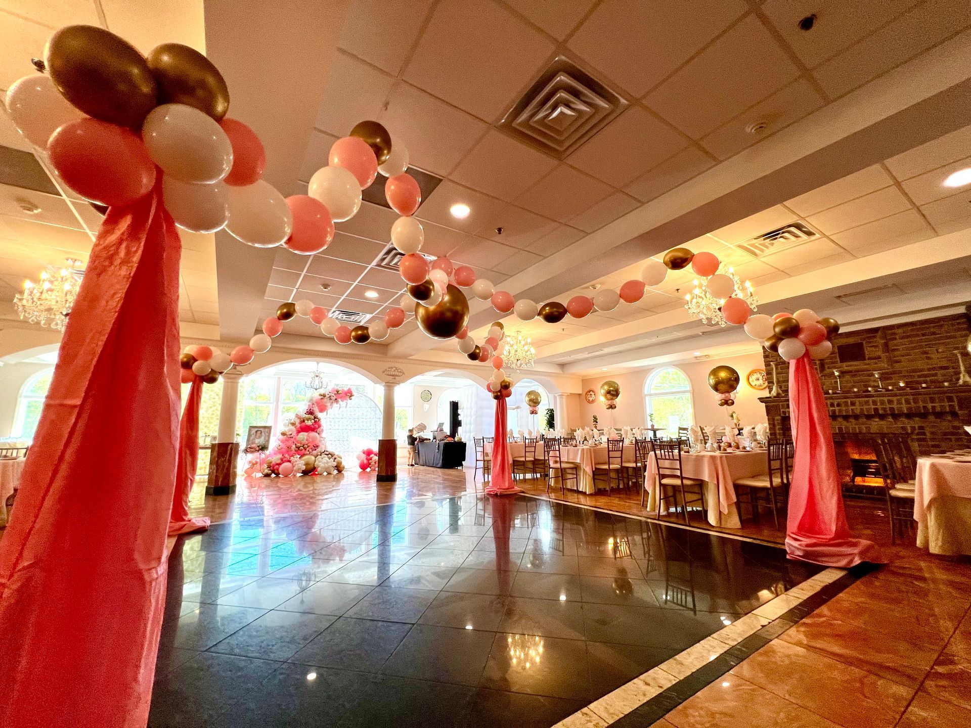 A large room with tables and chairs and balloons hanging from the ceiling.