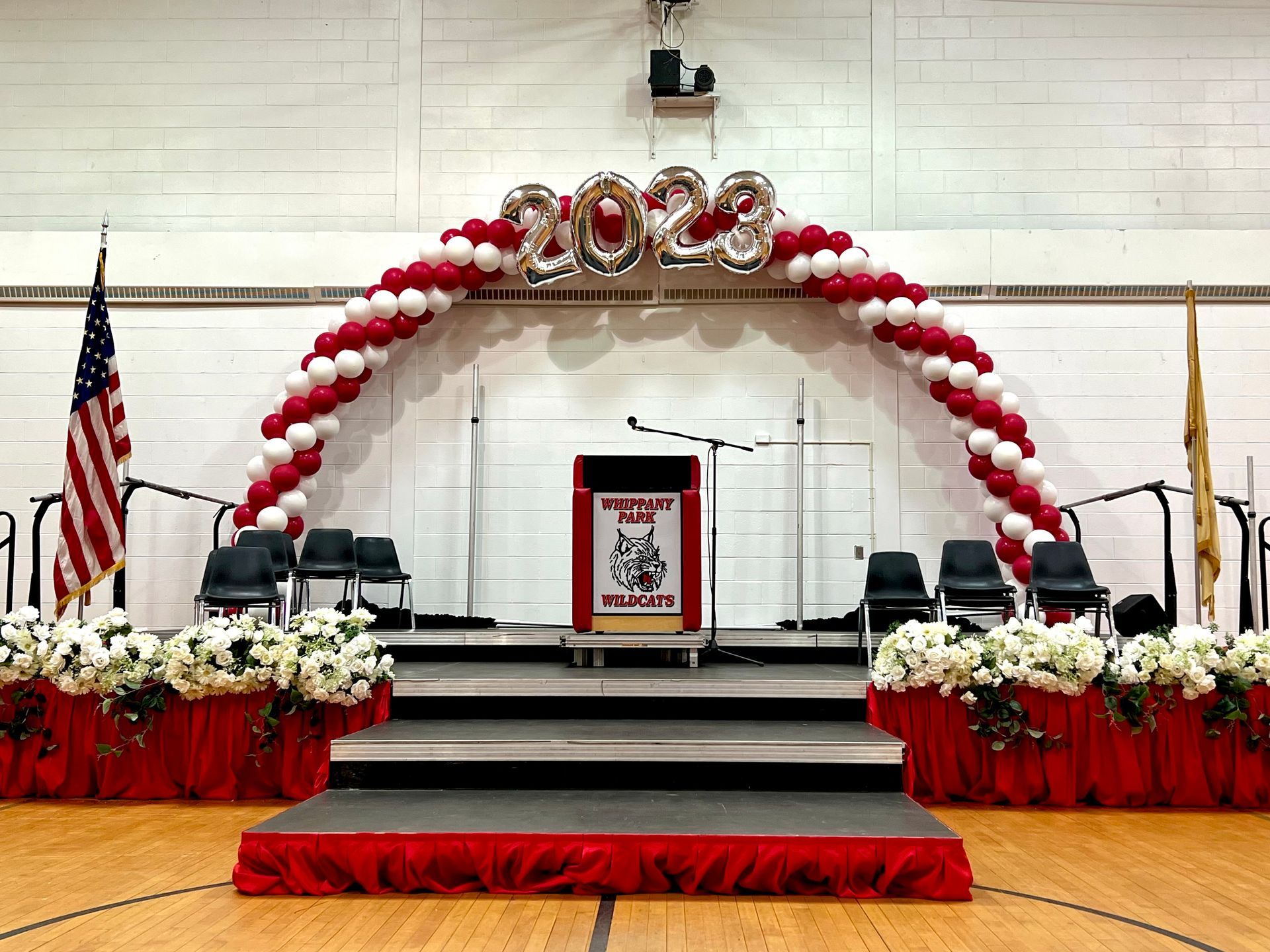 A stage decorated with balloons and flowers for a graduation ceremony.