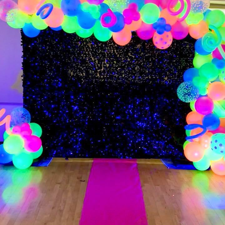 A room filled with glow in the dark balloons and a pink carpet.