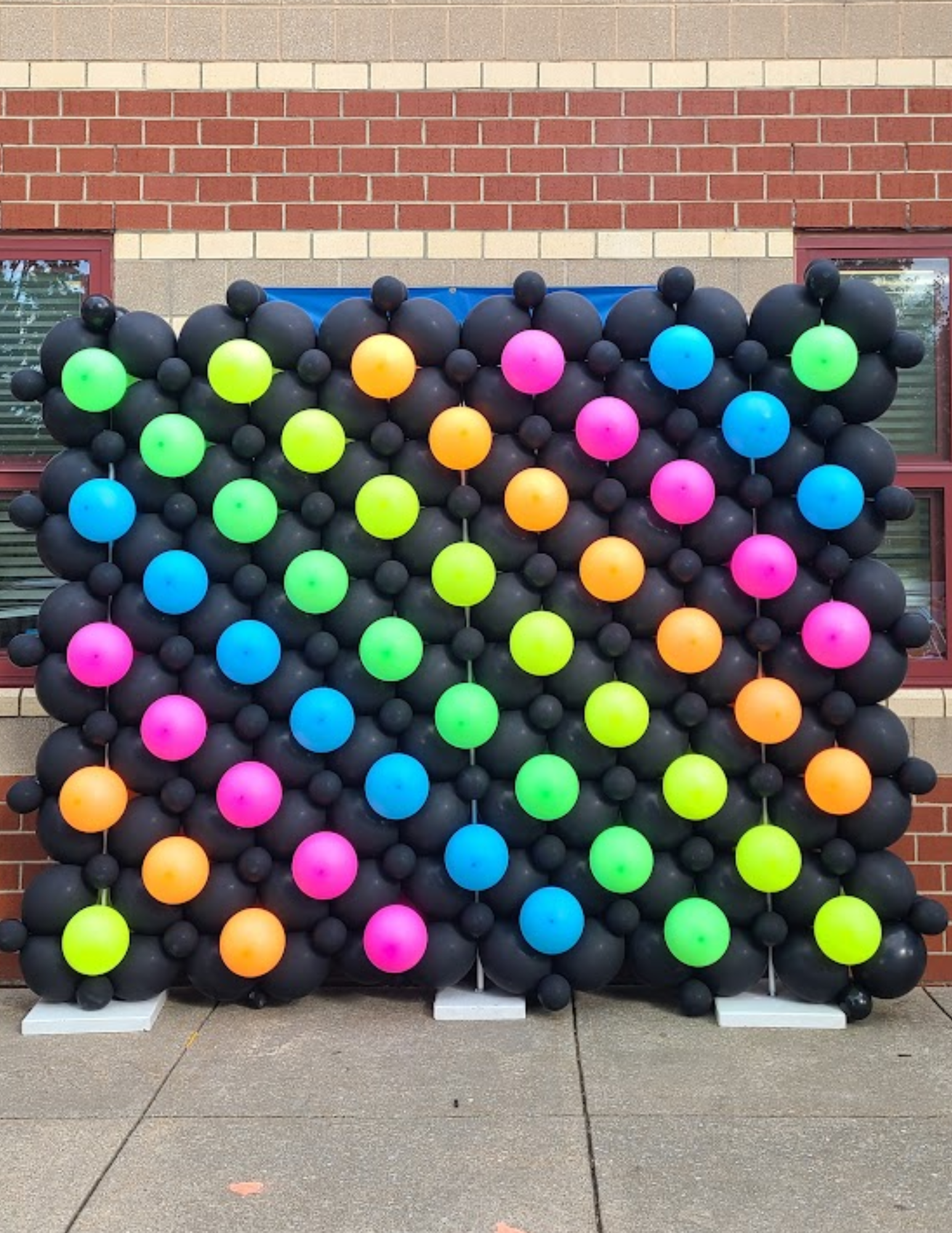 A wall made of black balloons with neon colored polka dots