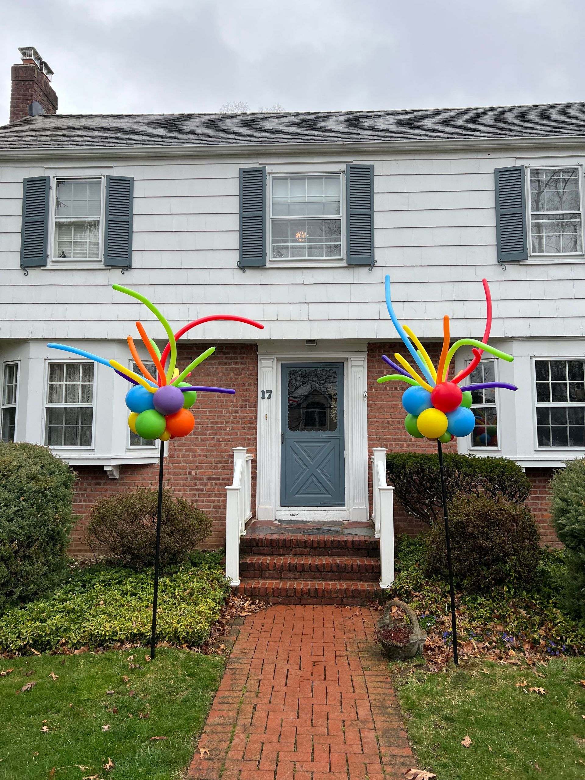 A house with a brick walkway and balloons in front of it.