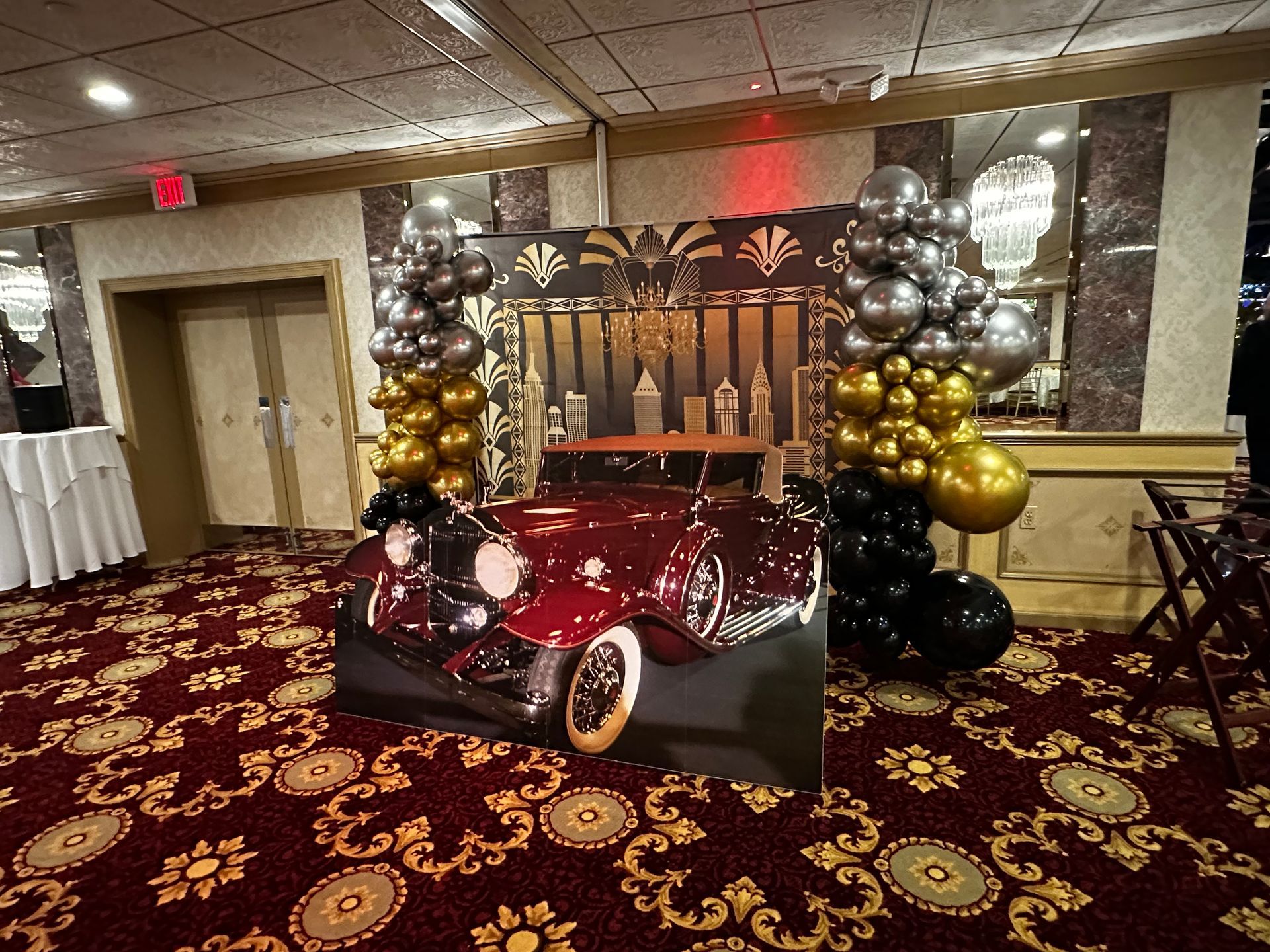 A picture of a car is surrounded by balloons in a room.
