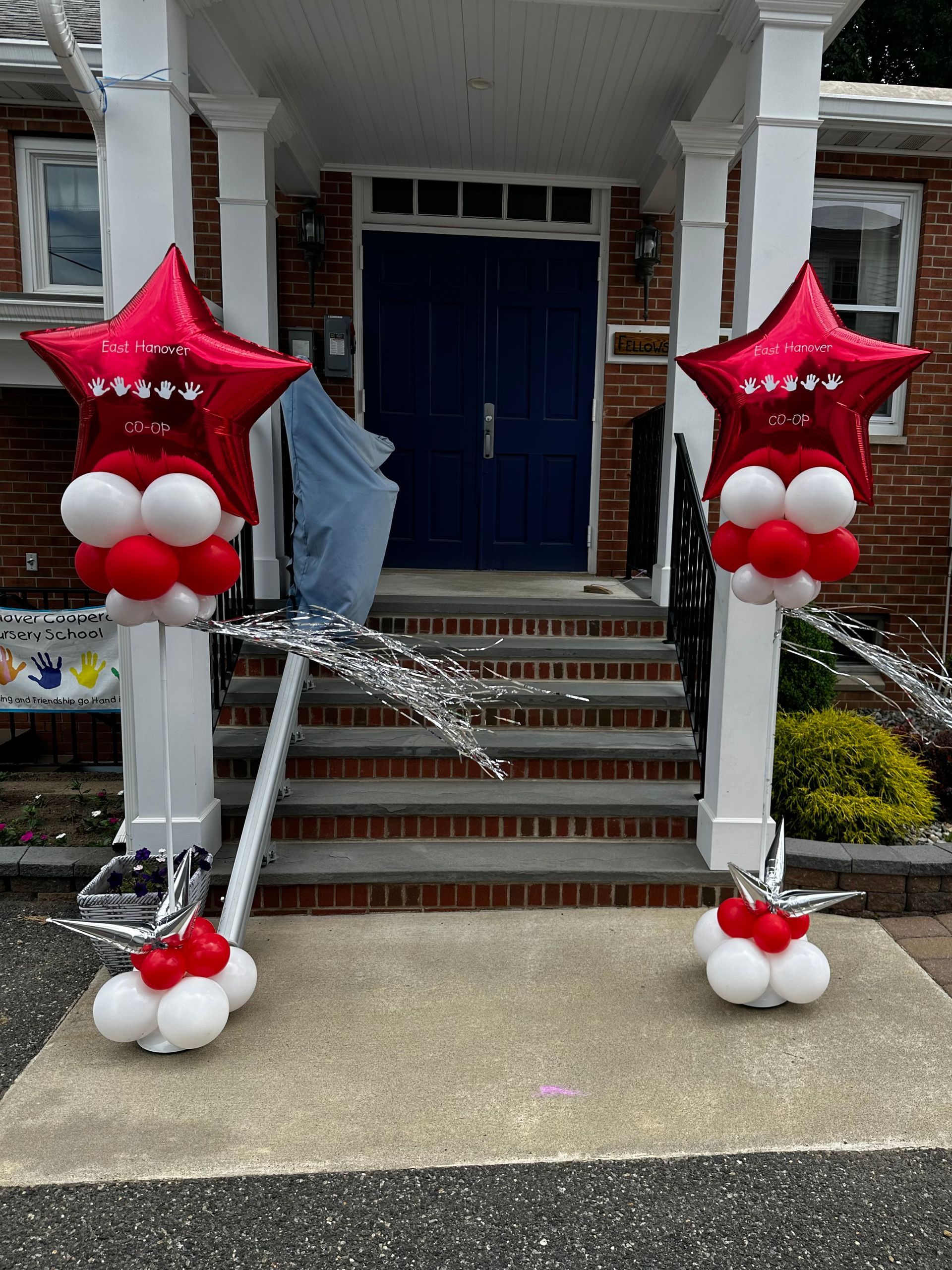 A couple of red and white balloons are sitting in front of a house.