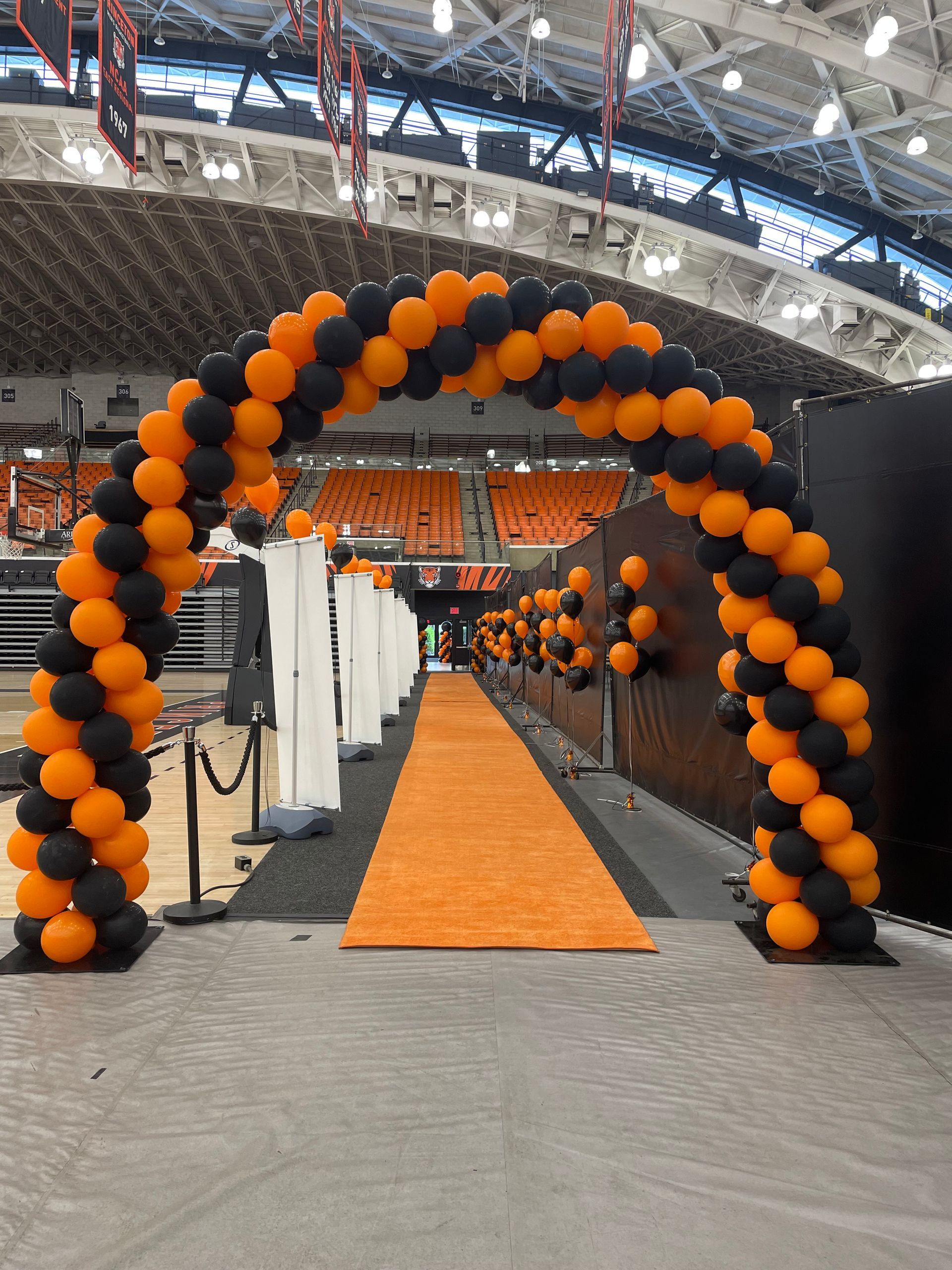 An orange and black balloon arch in a stadium