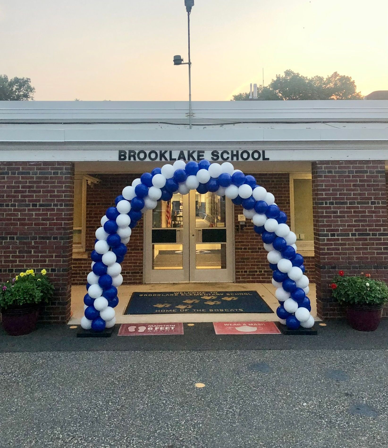A blue and white balloon arch is in front of the brooklake school