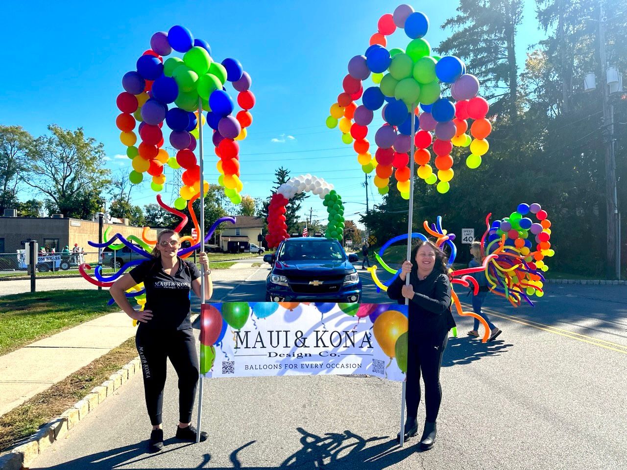 Two women holding balloons and a sign that says maui & kona
