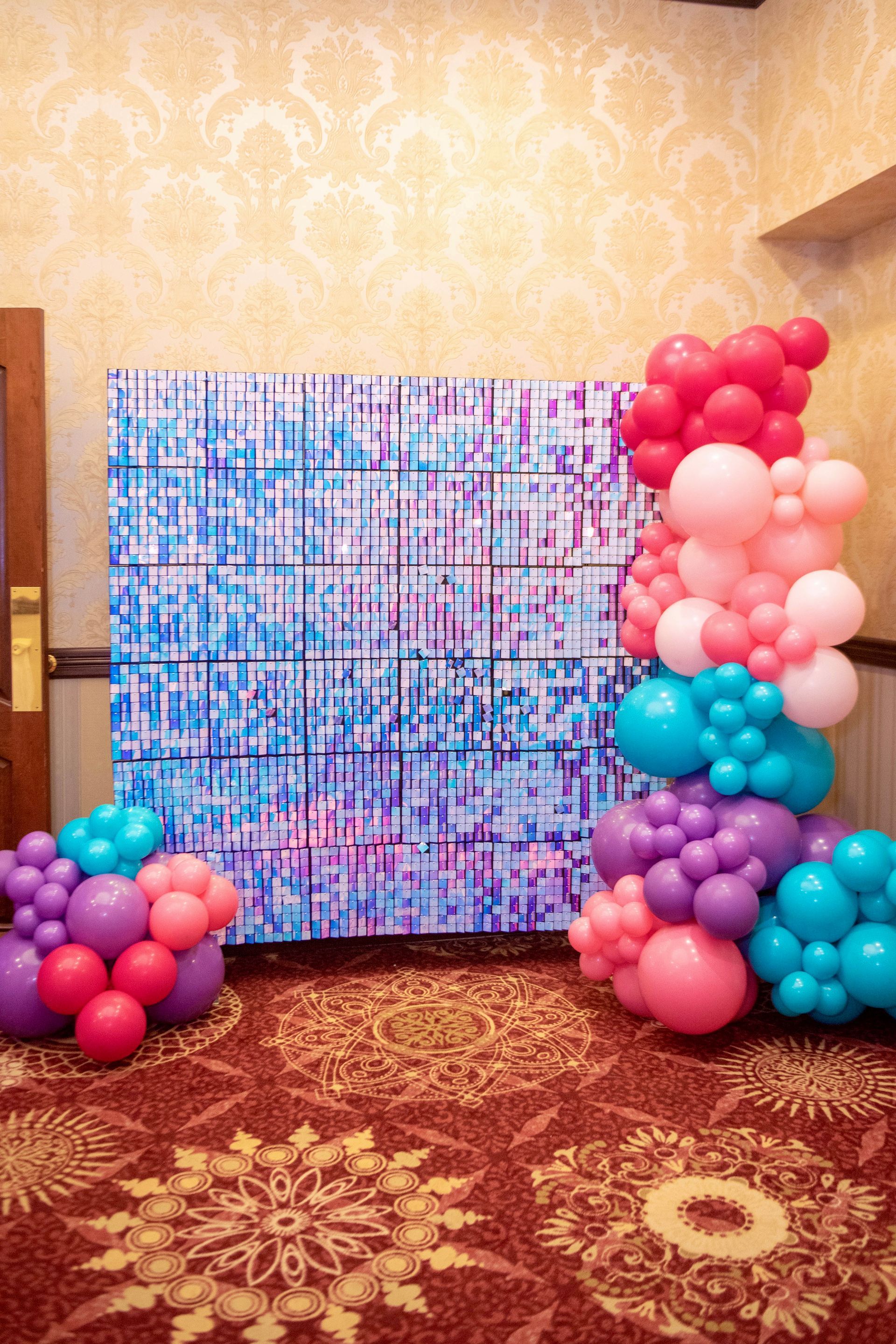 A room filled with balloons and a painting on the wall.