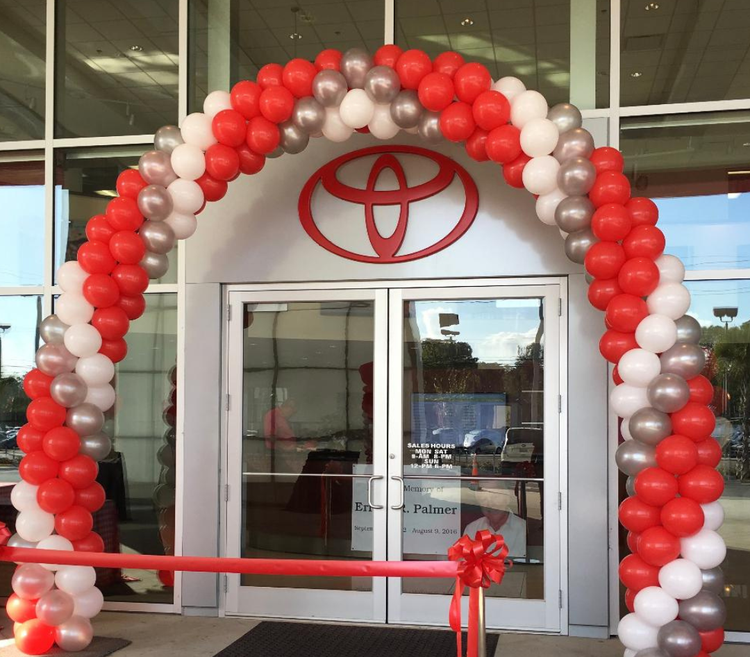 A red white and silver balloon arch in front of a toyota store