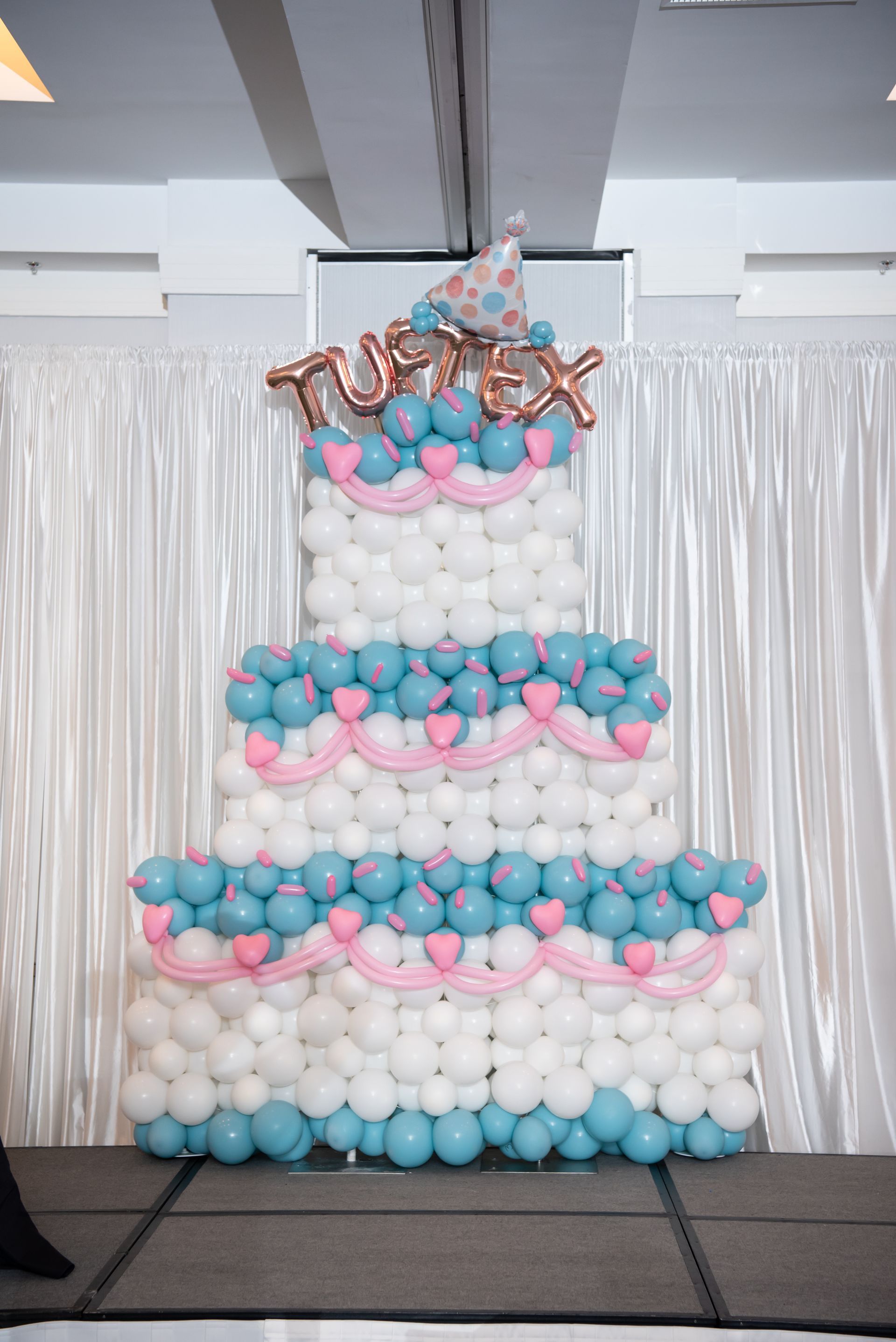 A cake made out of balloons is sitting on a stage.
