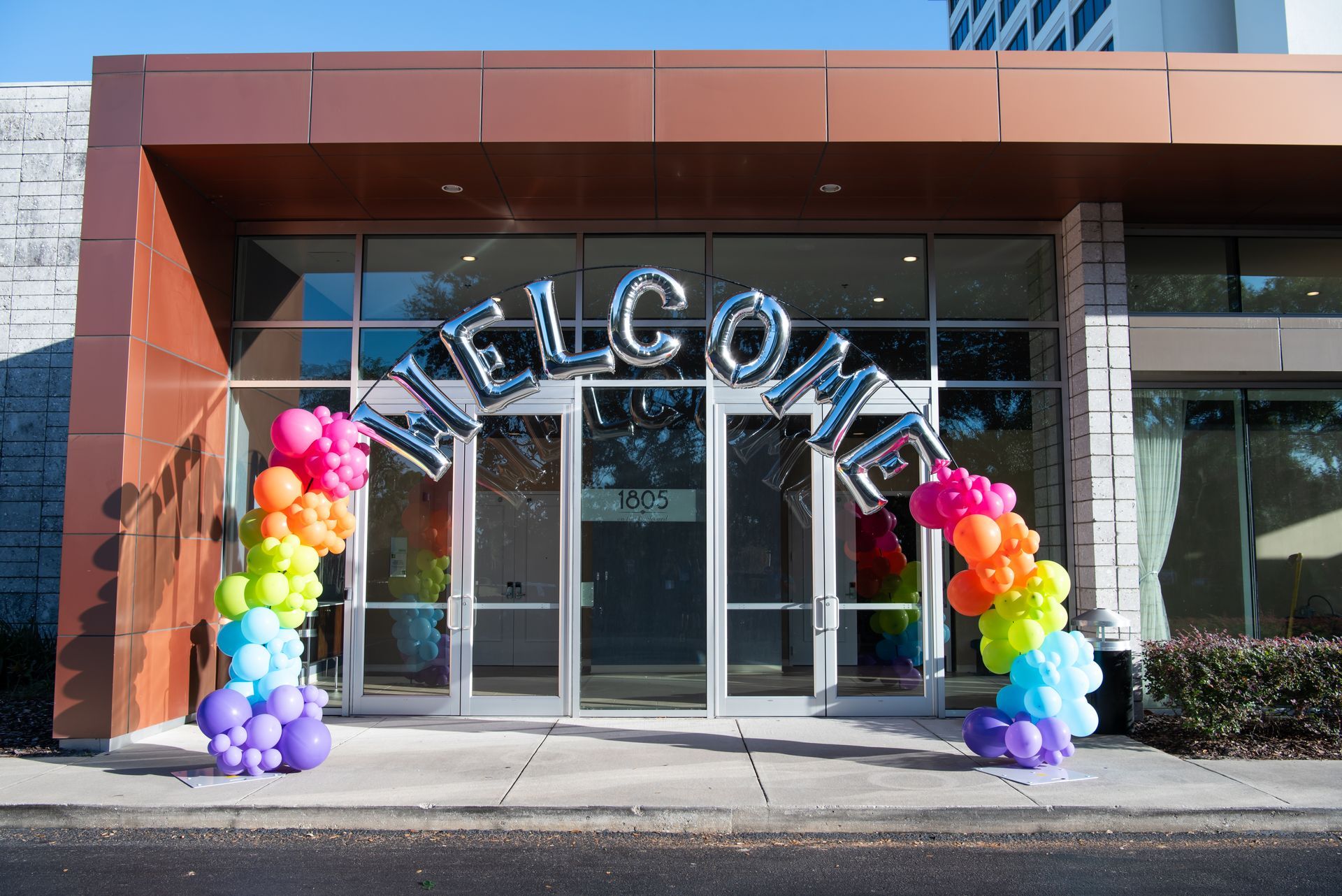 A welcome sign with balloons in front of a building