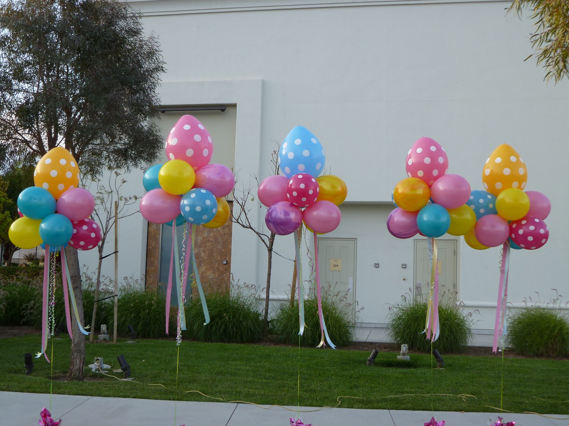 A bunch of colorful balloons in front of a white building