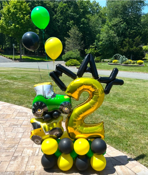 Balloon display for a 2nd birthday with tractor and number 2, green, yellow, and black balloons outside.