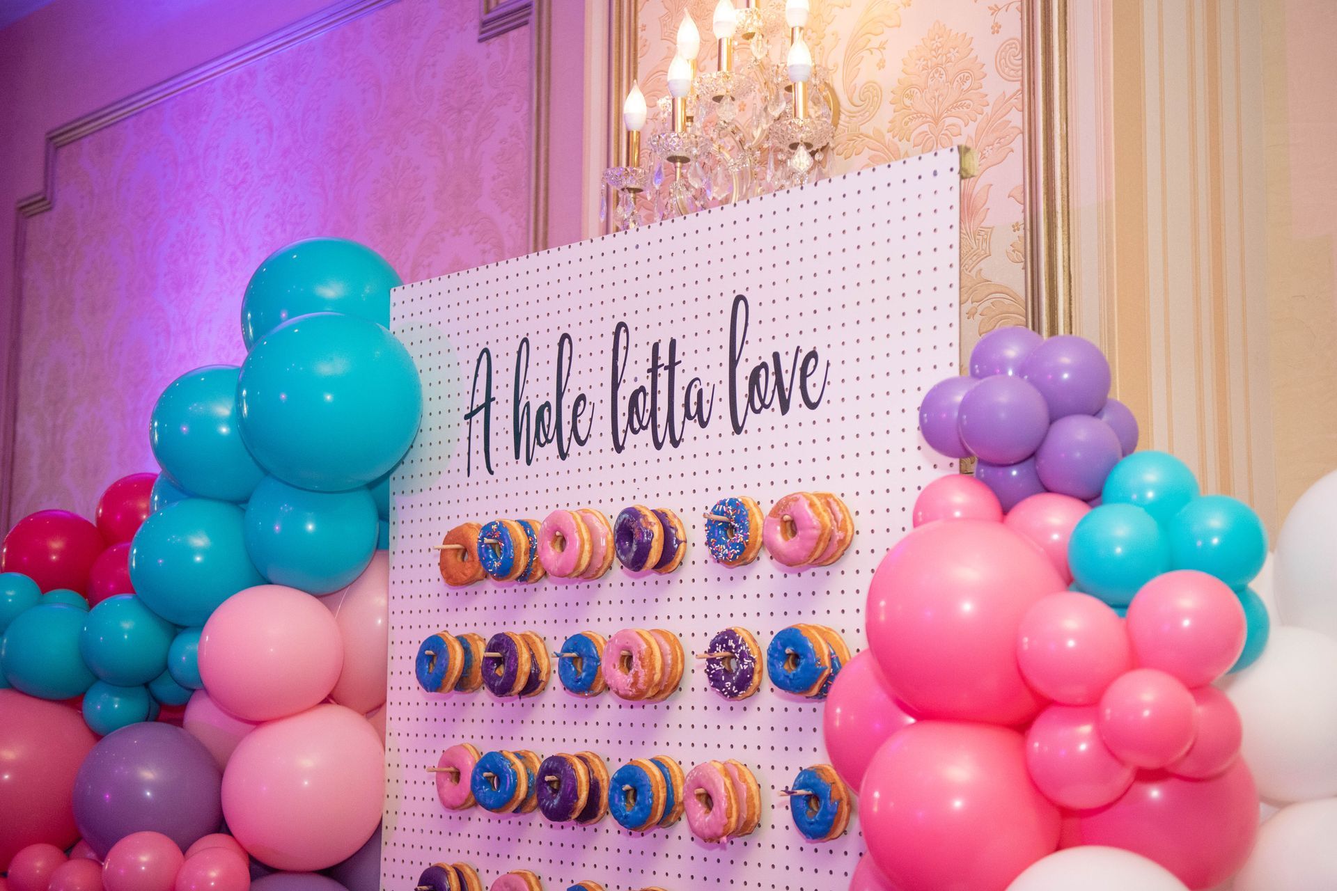 A wall decorated with balloons and donuts for a party.