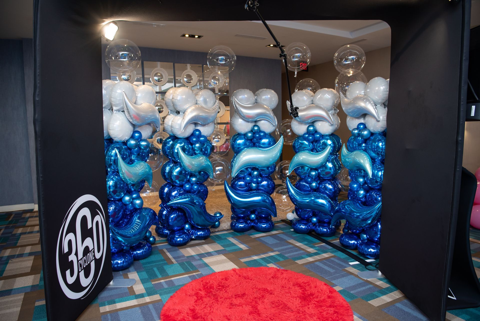 A room filled with blue and white balloons and a red rug.