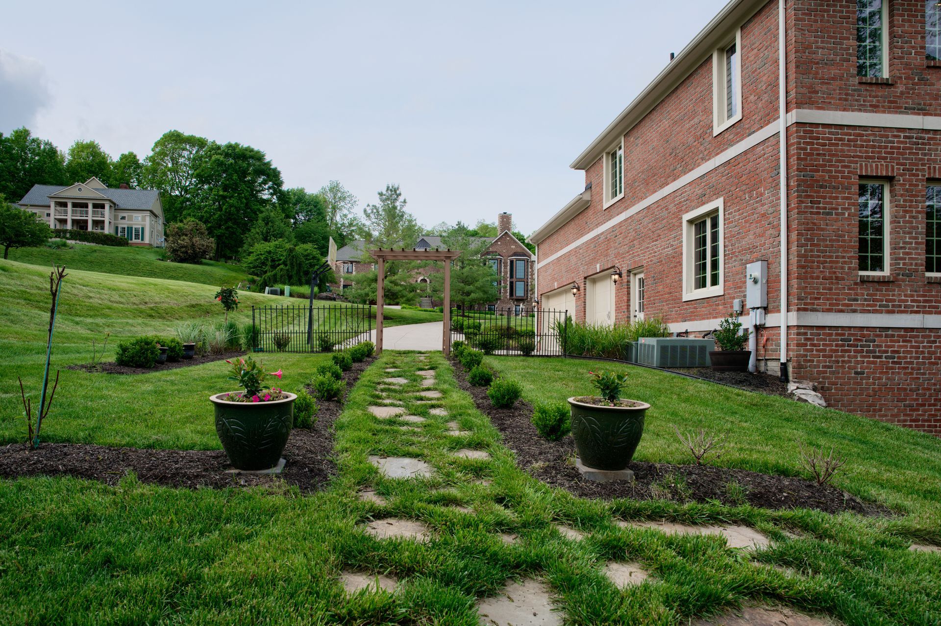 A brick house with a lush green lawn and a stone walkway leading to it.