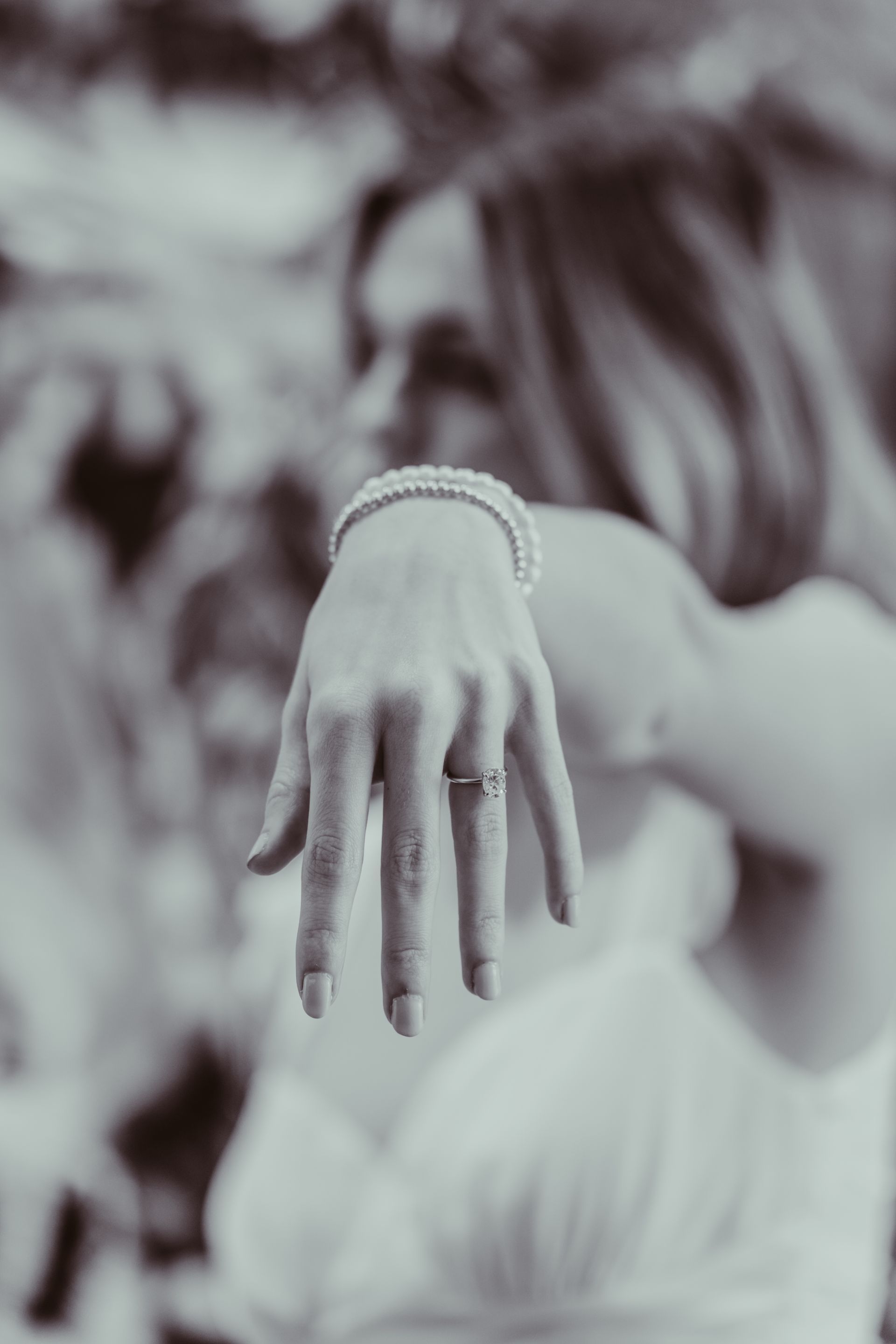 a black and white photo of a woman 's hand with a ring on it .