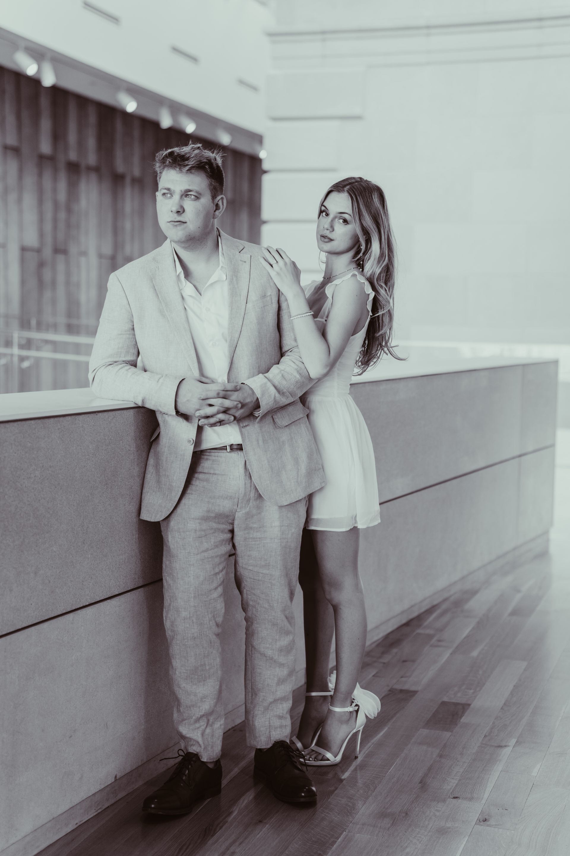 a man in a suit and a woman in a dress are standing next to each other .