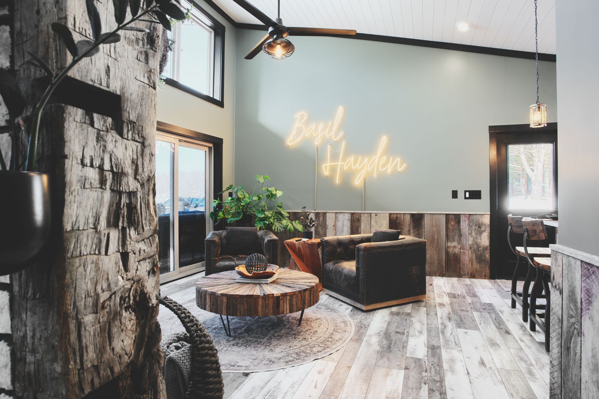A living room with a wooden table , chairs , and a neon sign on the wall.