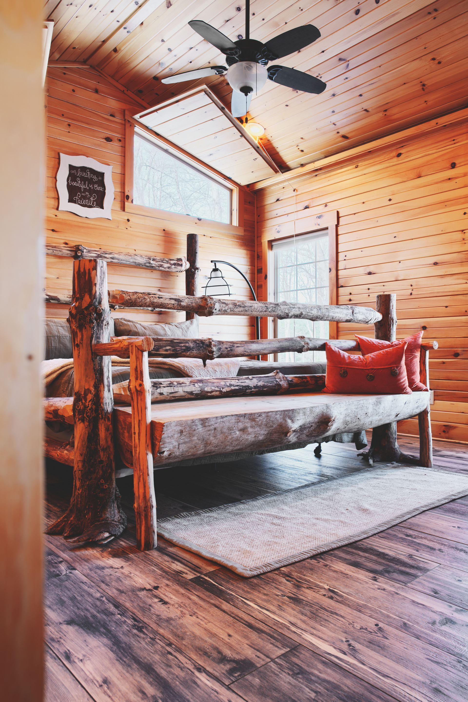 A wooden room with a wooden bench and a ceiling fan.
