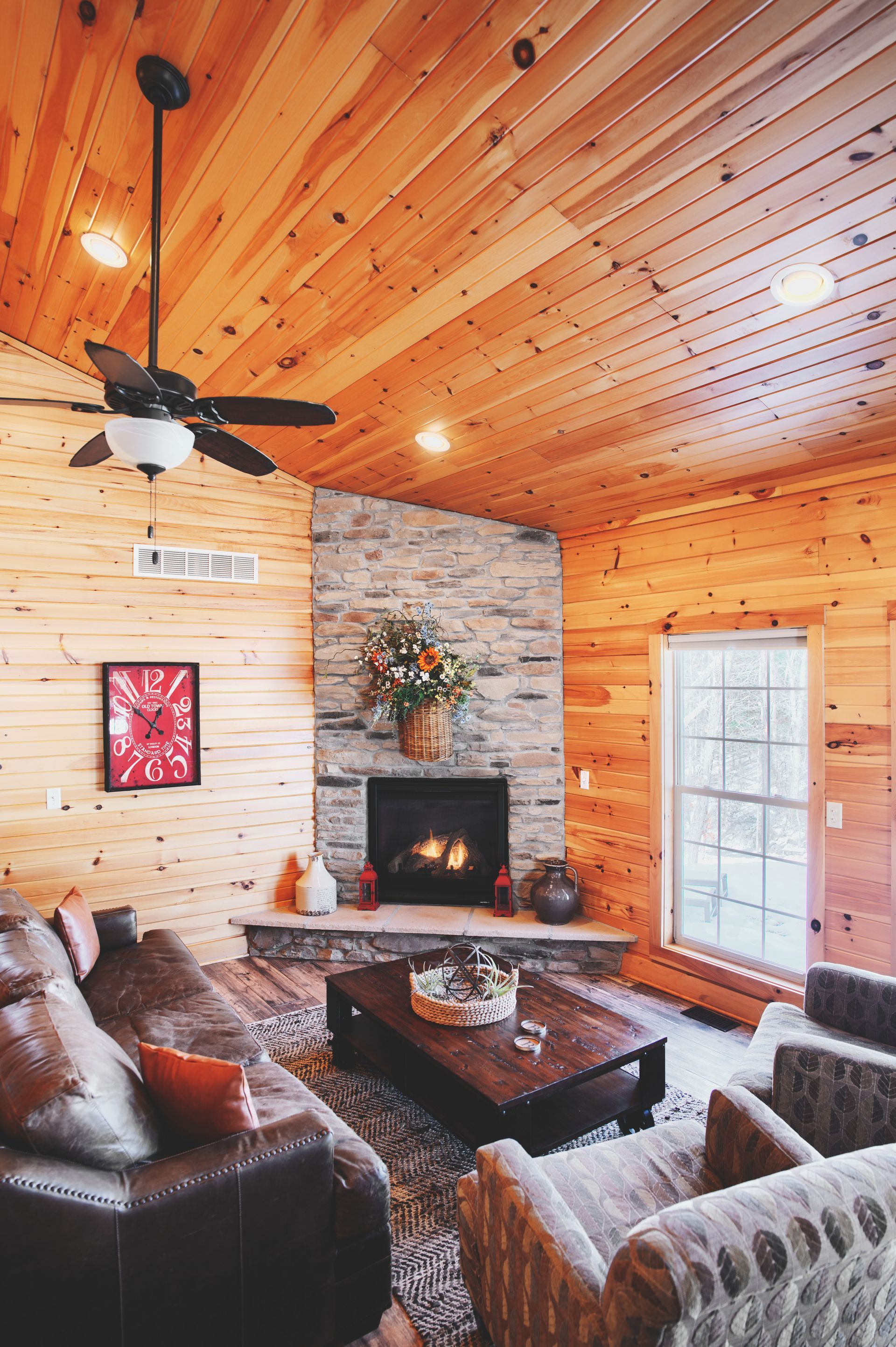 A living room with a ceiling fan and a fireplace.