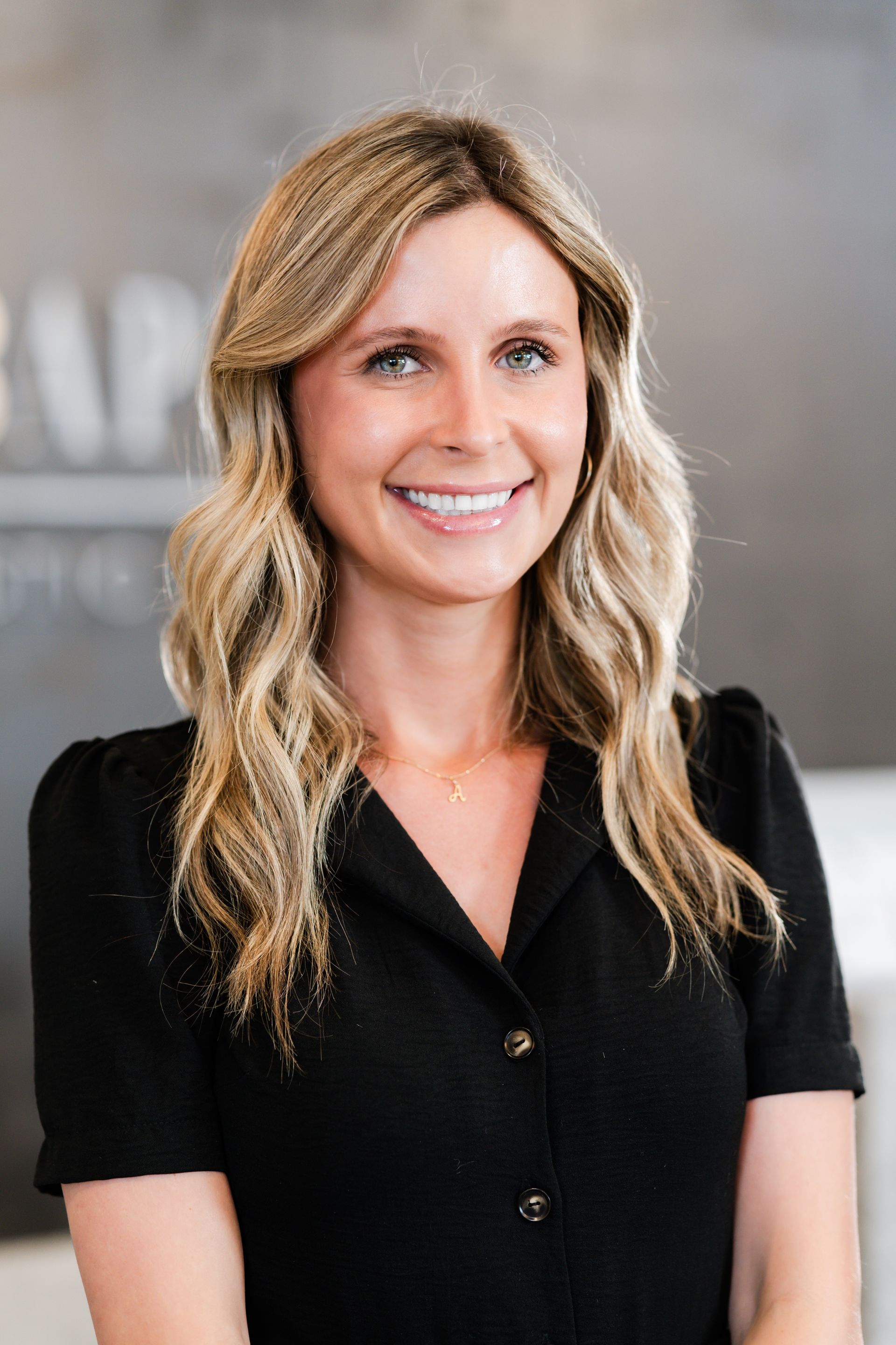 A woman in a black shirt is smiling for the camera.