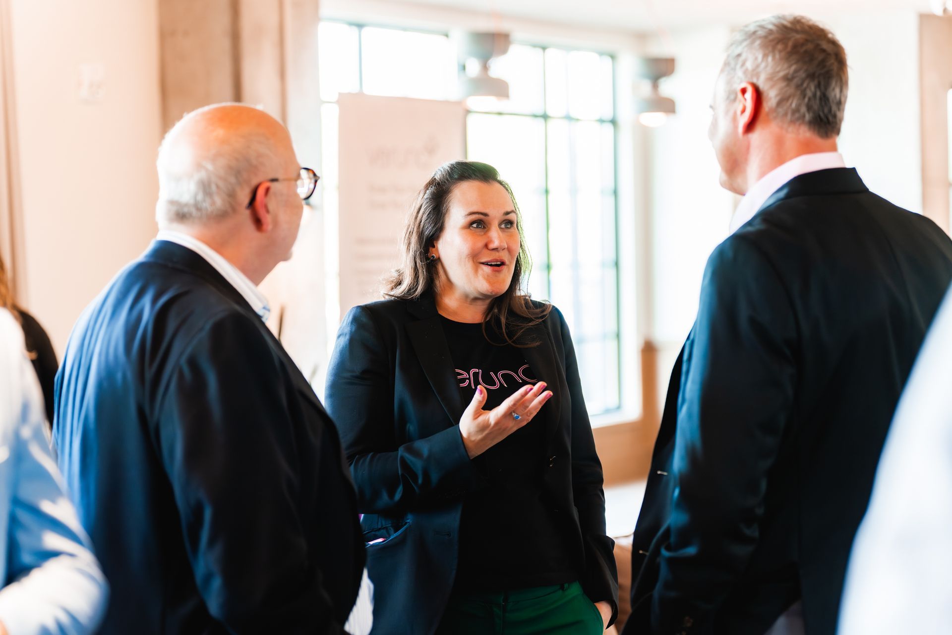 A group of people are standing around talking to each other in a room.