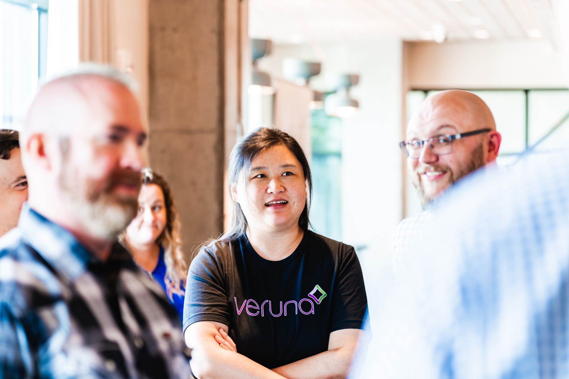 A group of people are standing around talking to each other in a room.