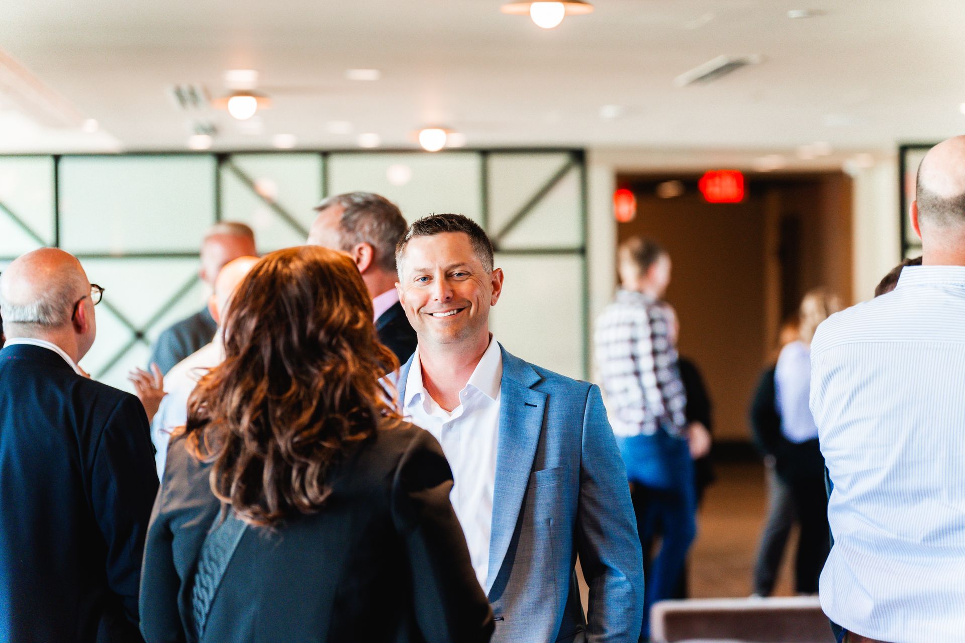 A group of people are standing in a room talking to each other.