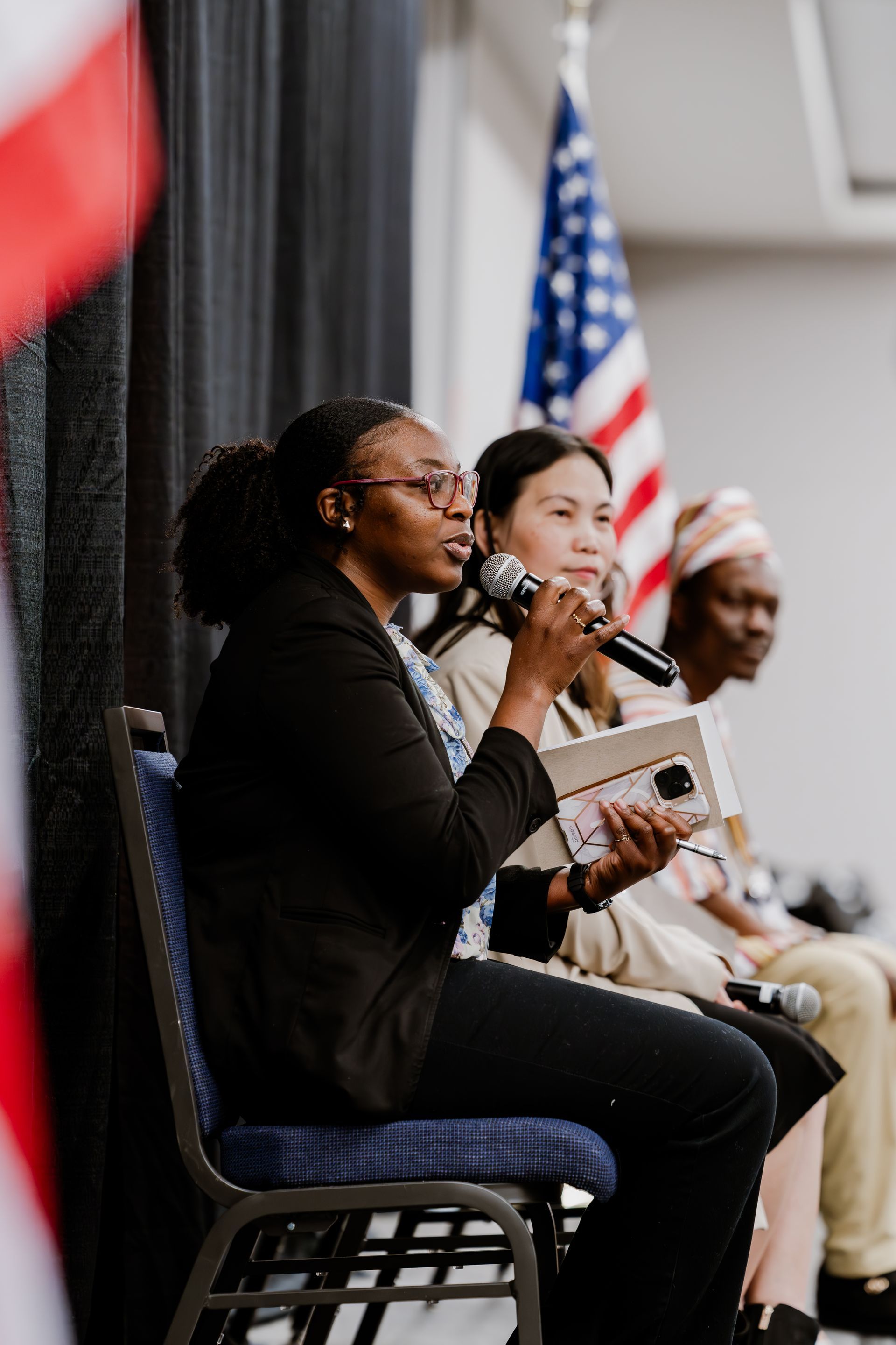 A woman is sitting in a chair holding a microphone.