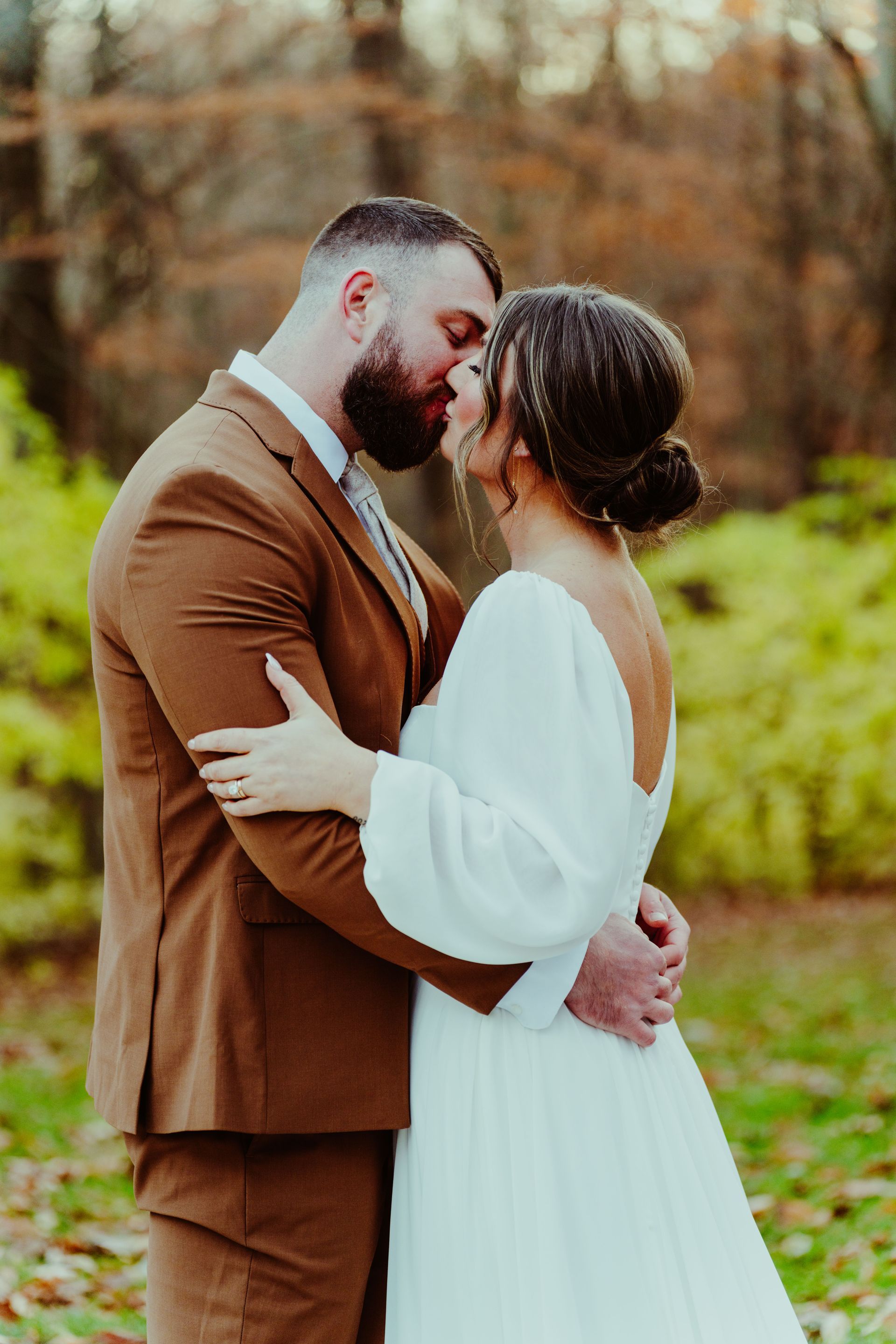 a bride in a wedding dress is standing in a field holding a bouquet of flowers .