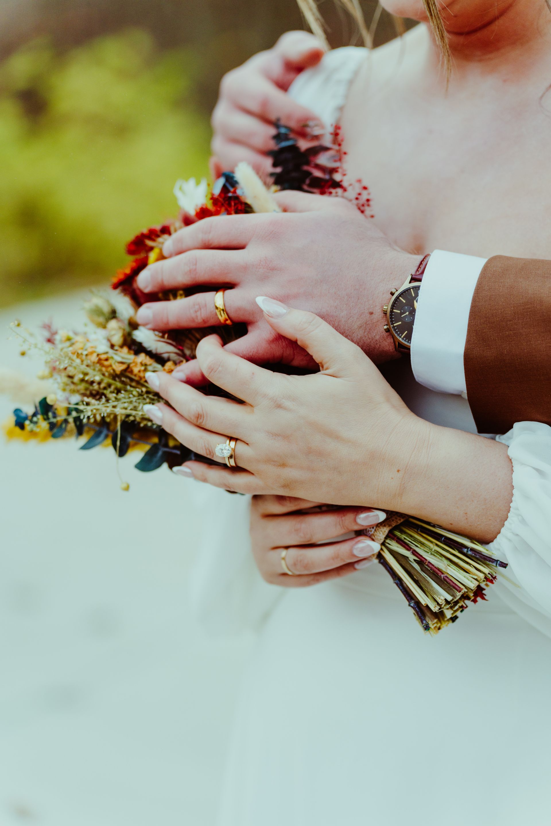 A close up of a bride and groom holding a bouquet of flowers.