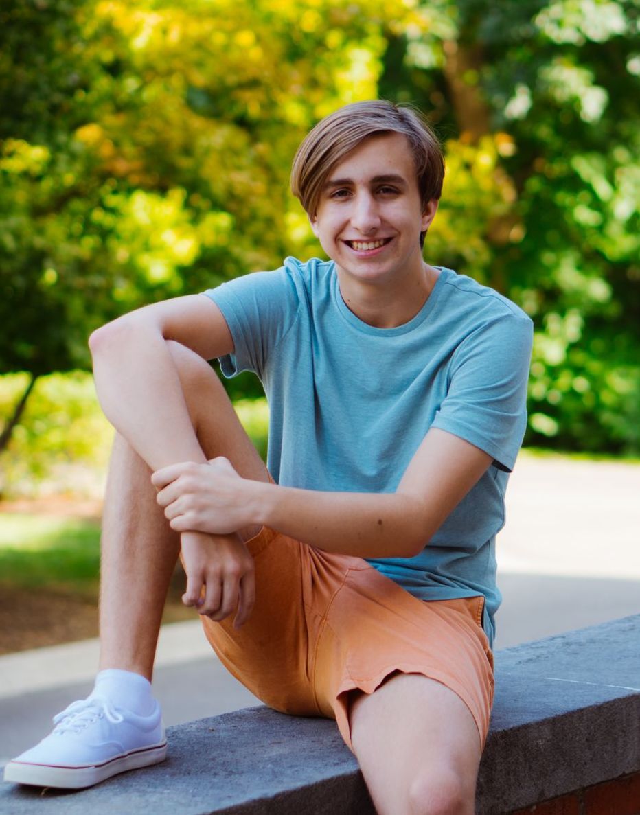 high school senior in a blue shirt and orange shorts is sitting on a bench .