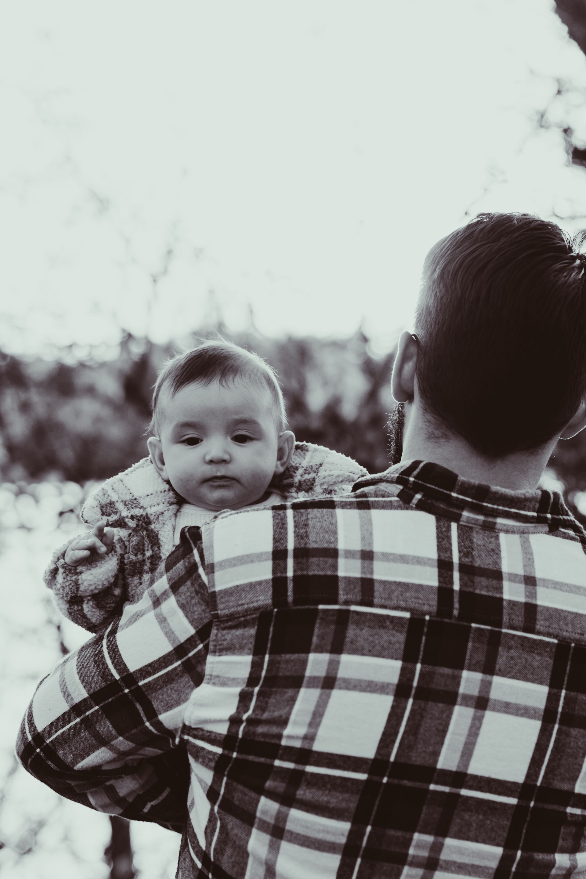a man in a plaid shirt is holding a baby in his arms .