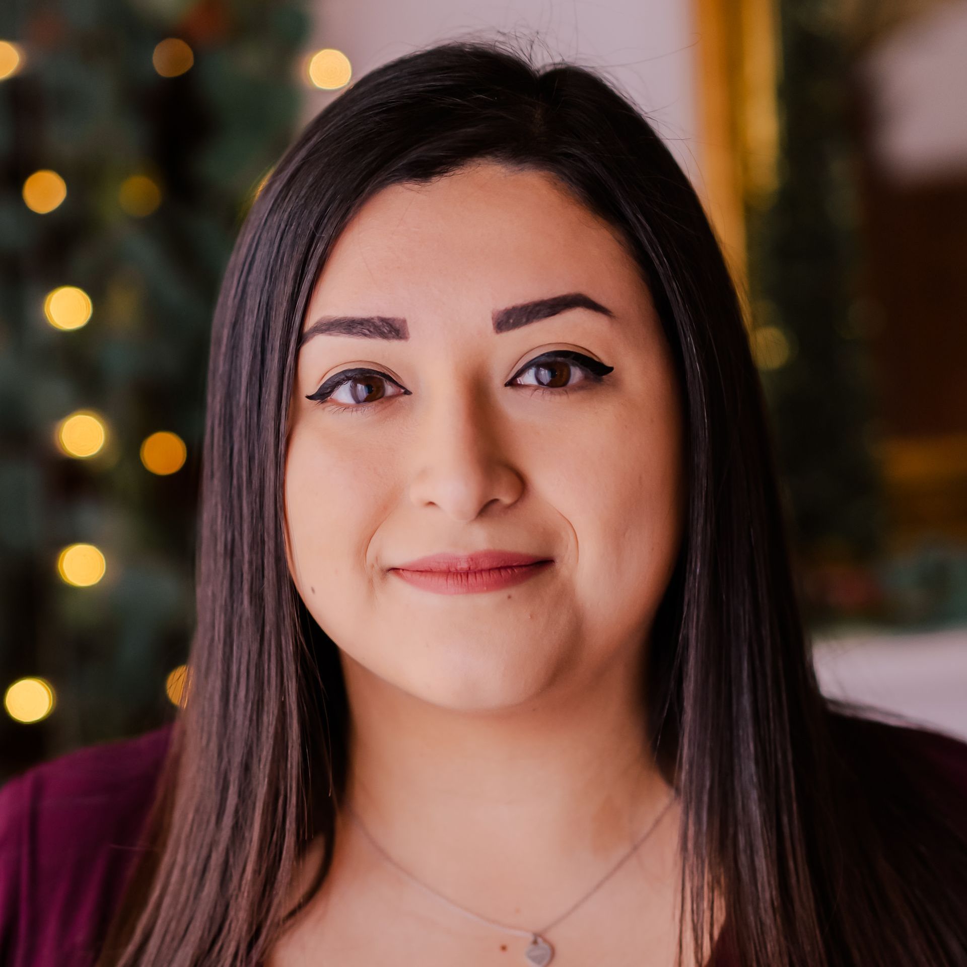 a close up of a woman 's face with a christmas tree in the background .