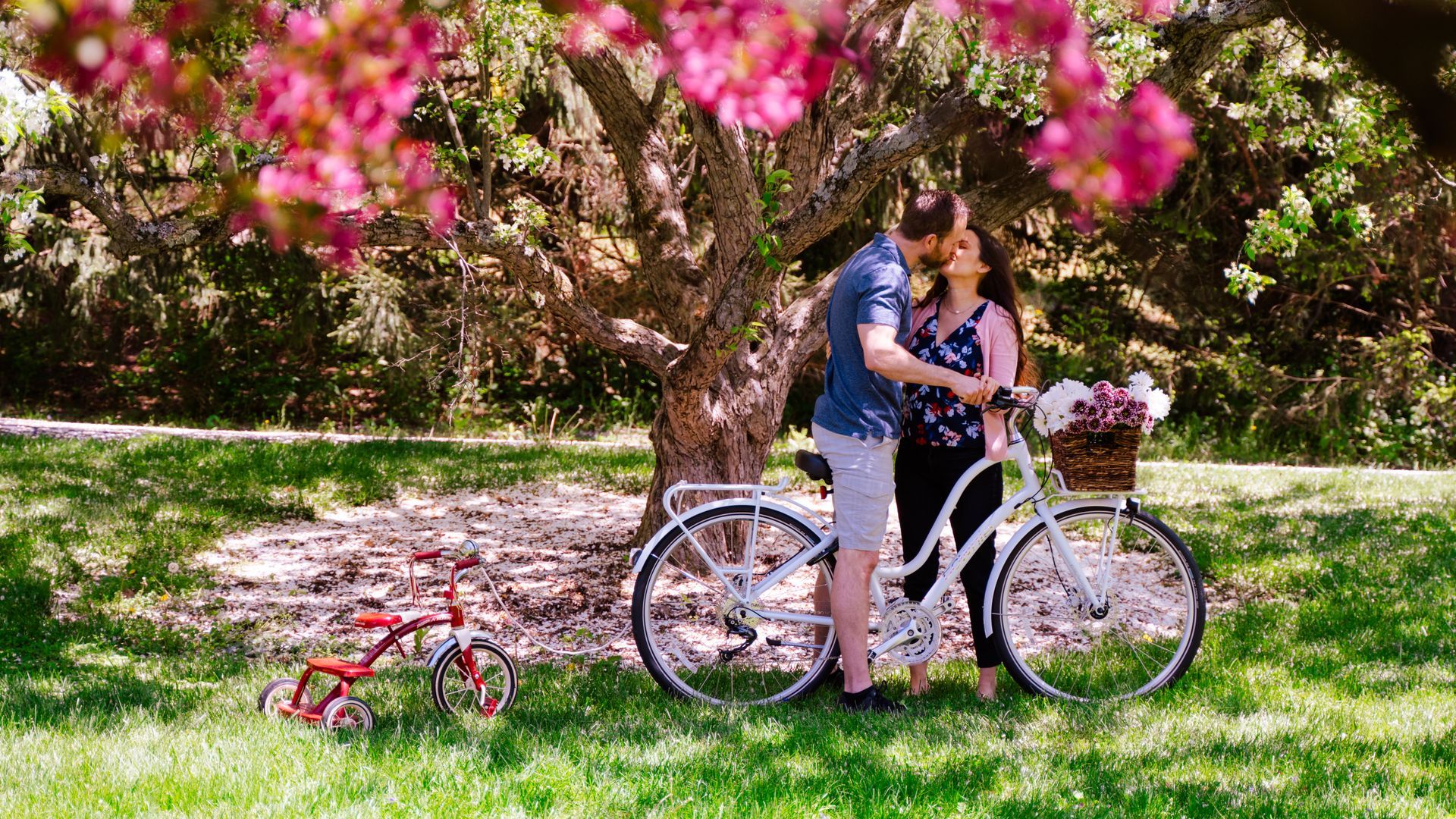a man and a woman are standing next to a bicycle in a park .