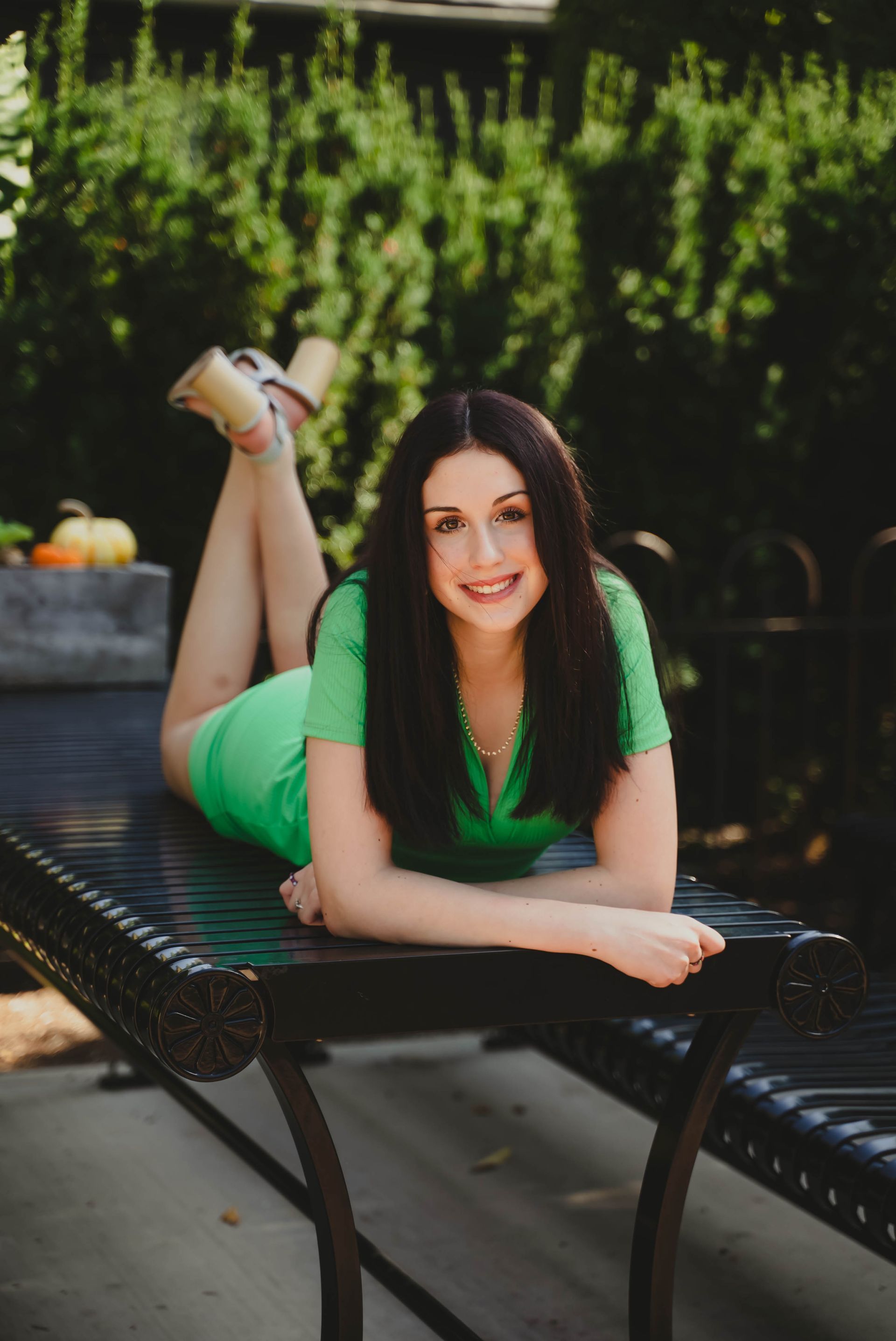a woman in a green dress is laying on a bench with her legs crossed .