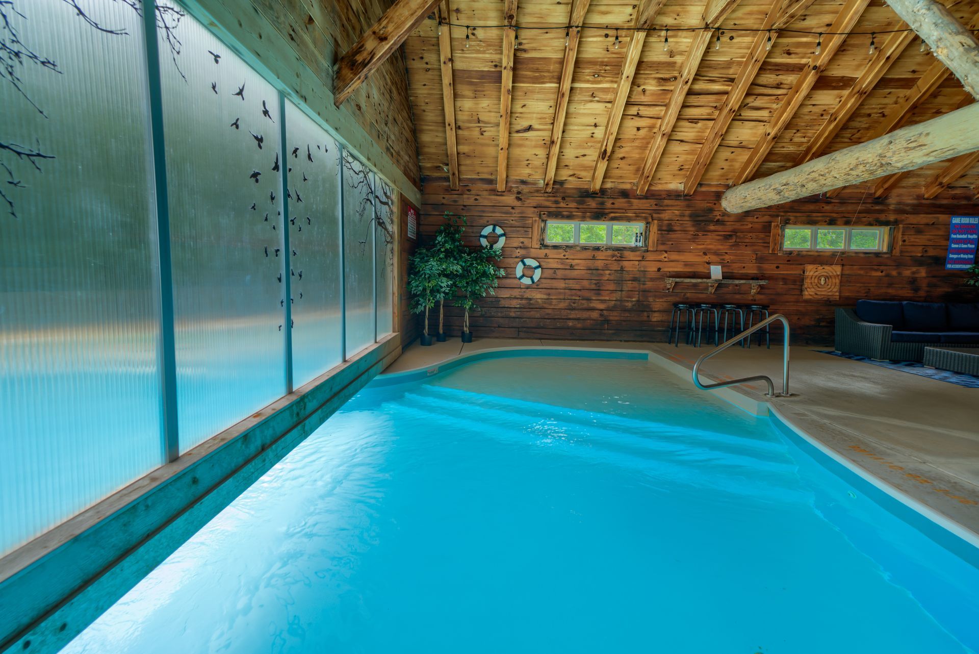 a large indoor swimming pool in a cabin with a wooden ceiling .