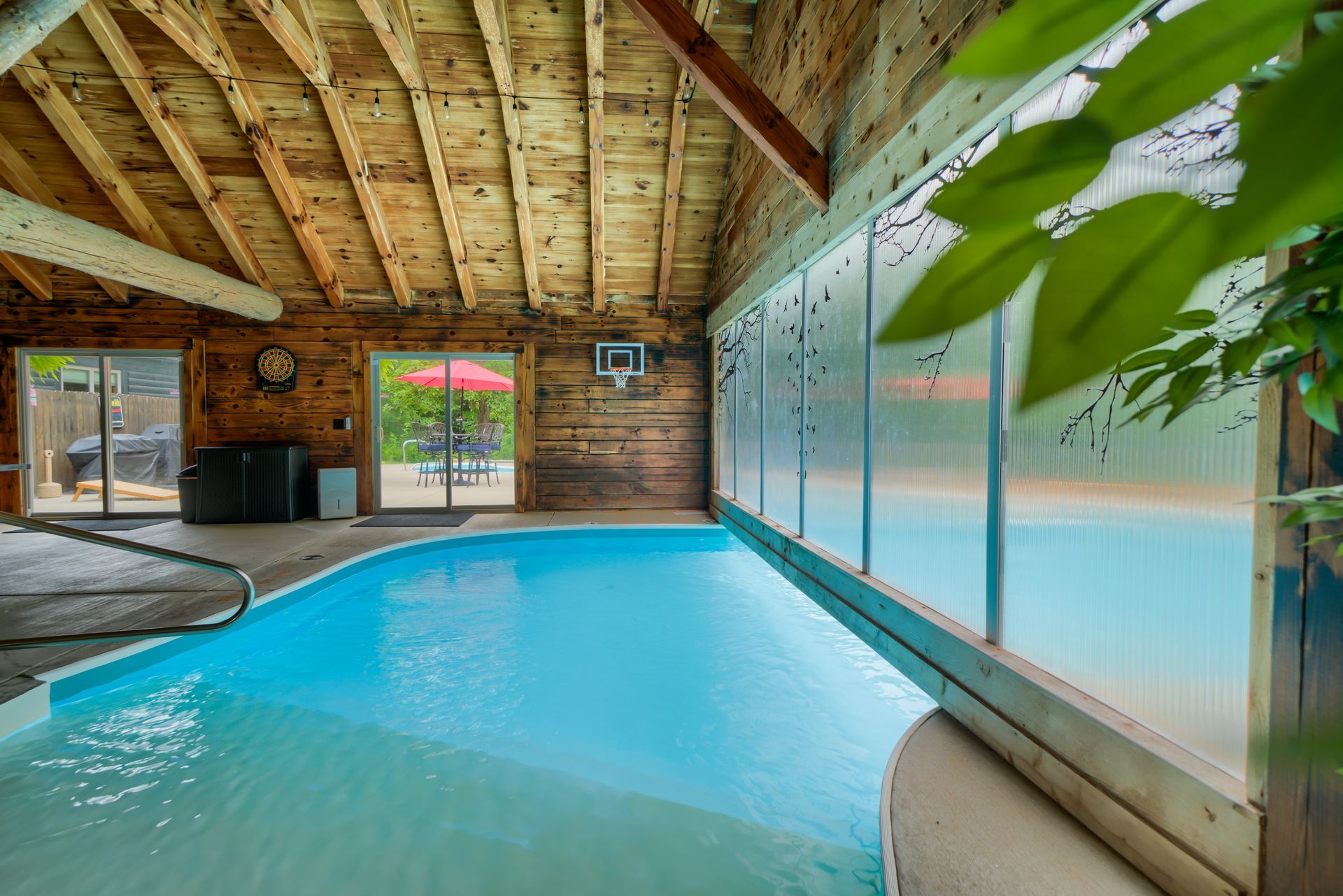 A large indoor swimming pool with a wooden ceiling and a lot of windows.
