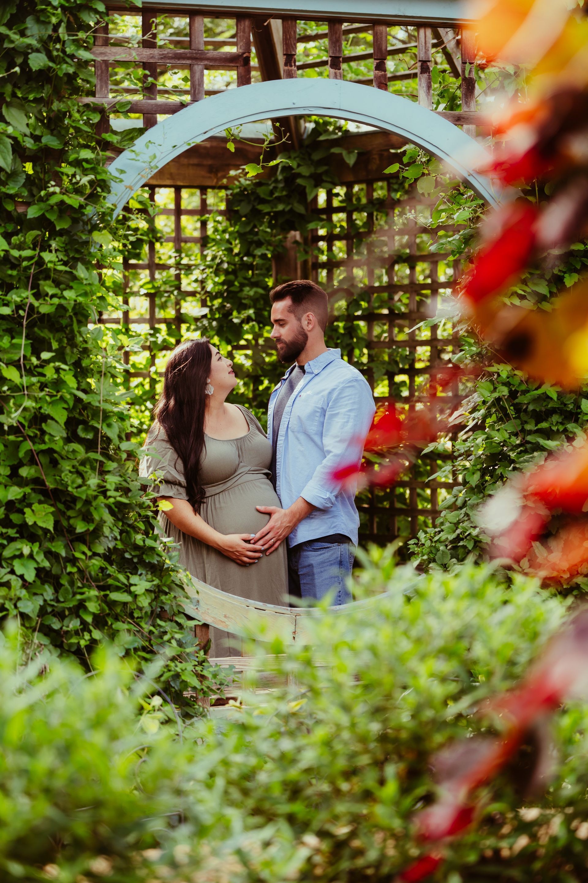 a pregnant woman and a man are holding hands in a garden .