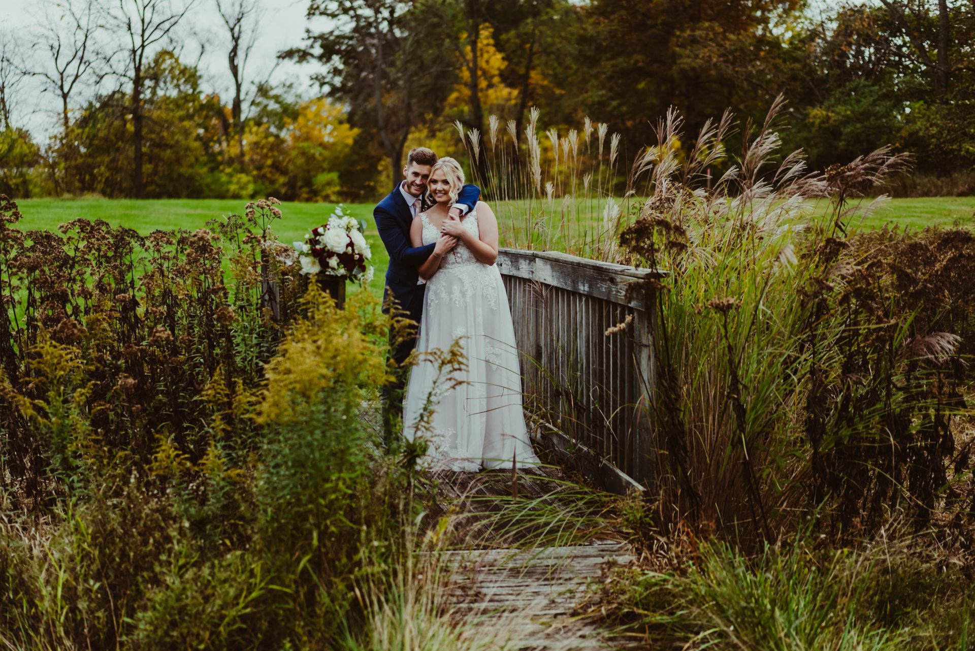 a black and white photo of a bride and groom leaning against a wall .