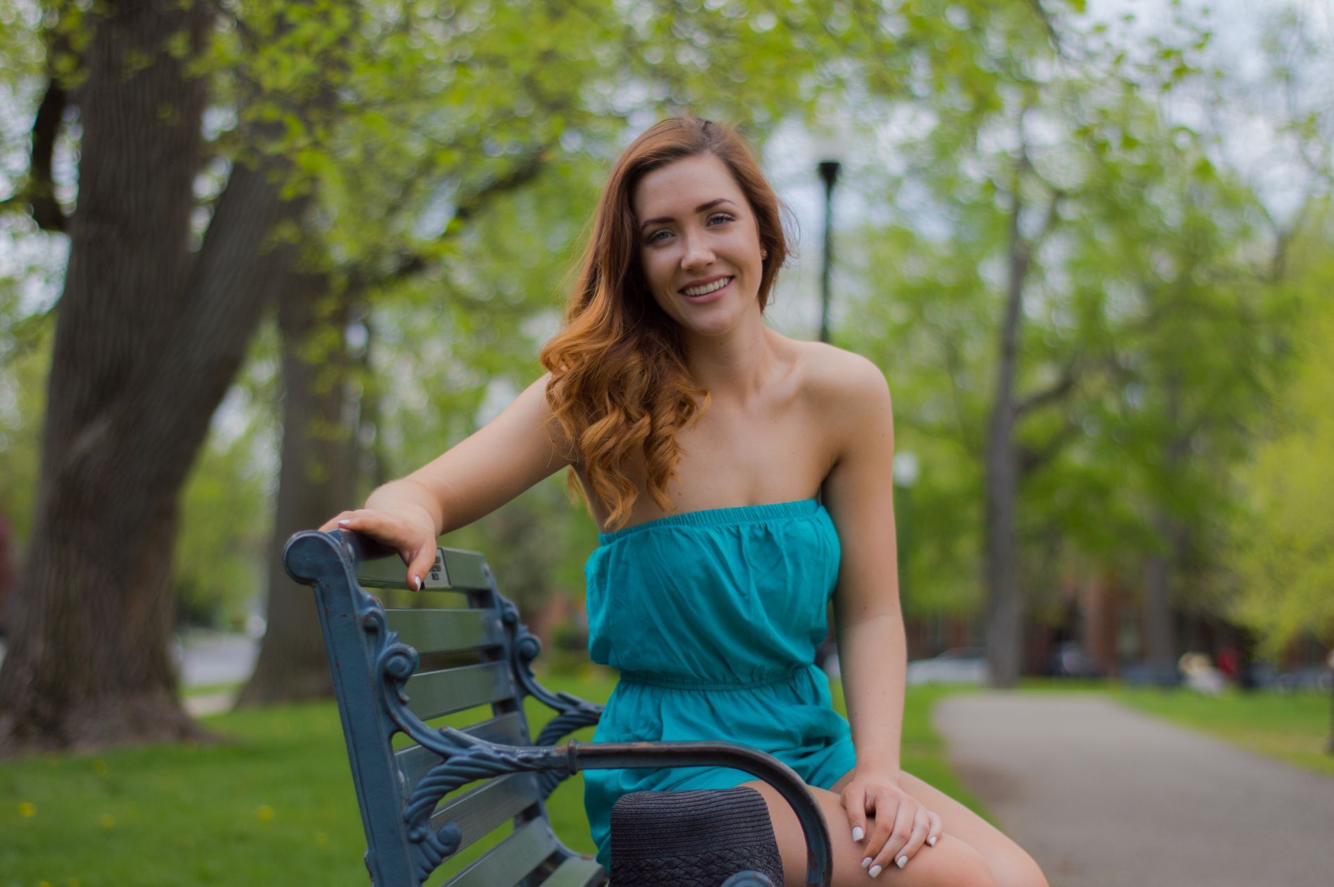 a woman in a blue dress is sitting on a park bench .