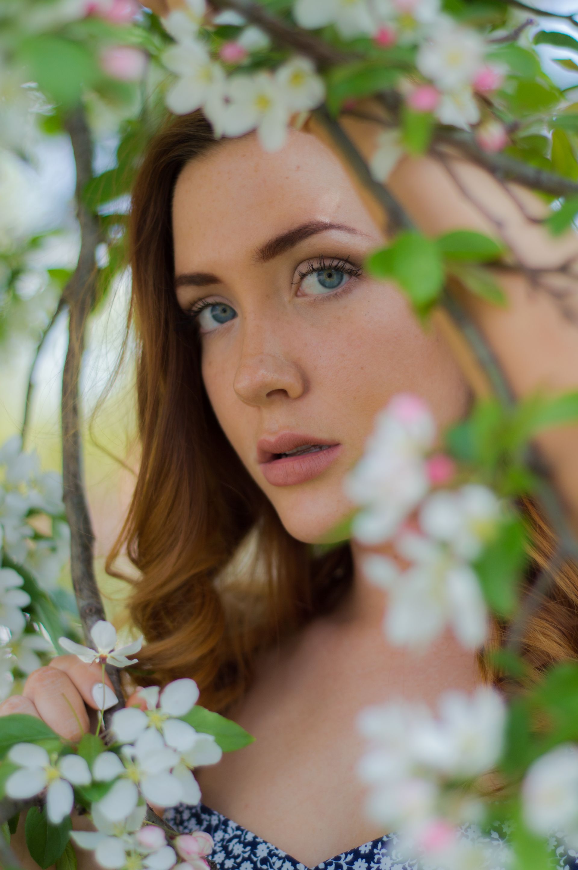 a woman is standing under a tree with white flowers .