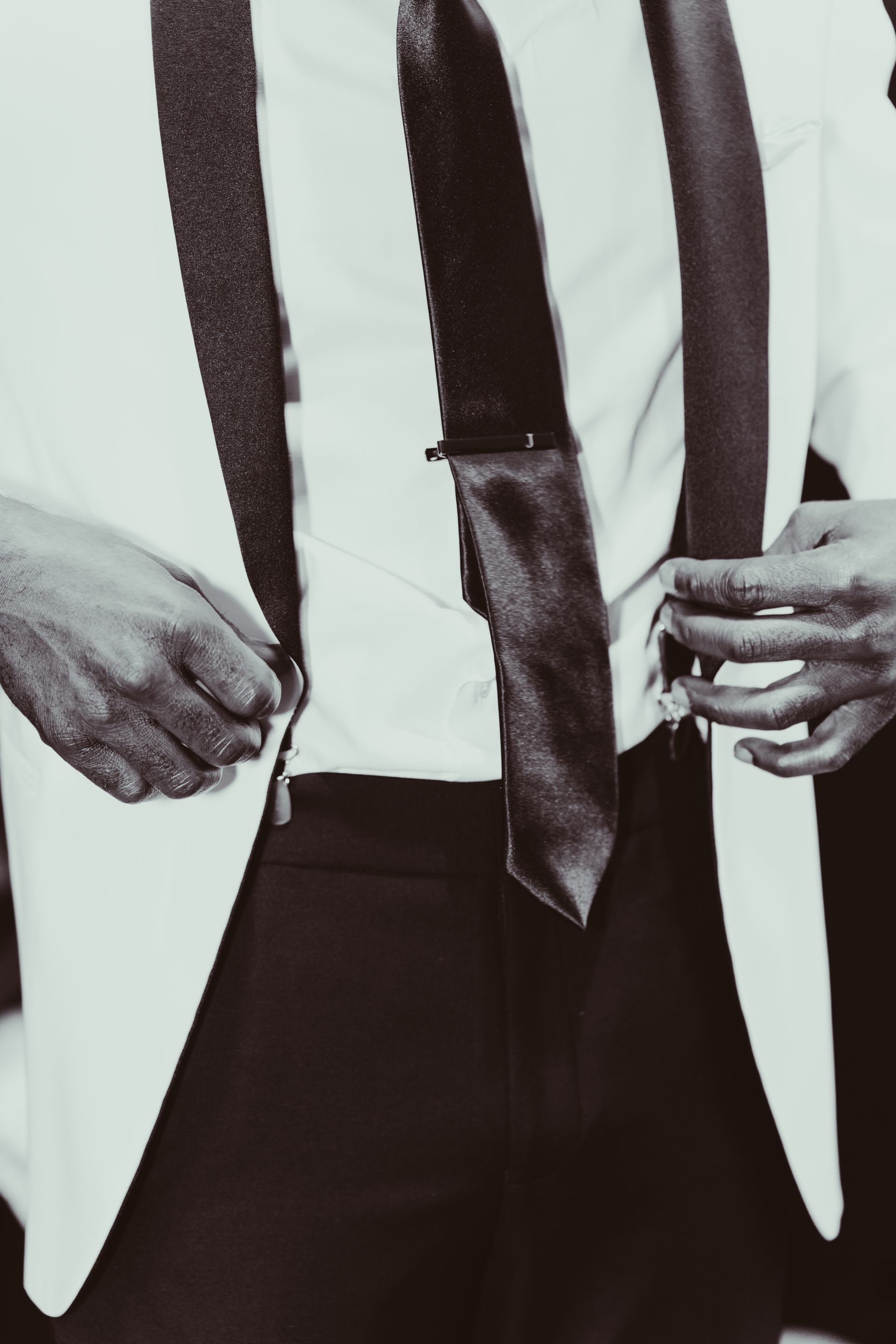 A man in a suit and tie is adjusting his jacket